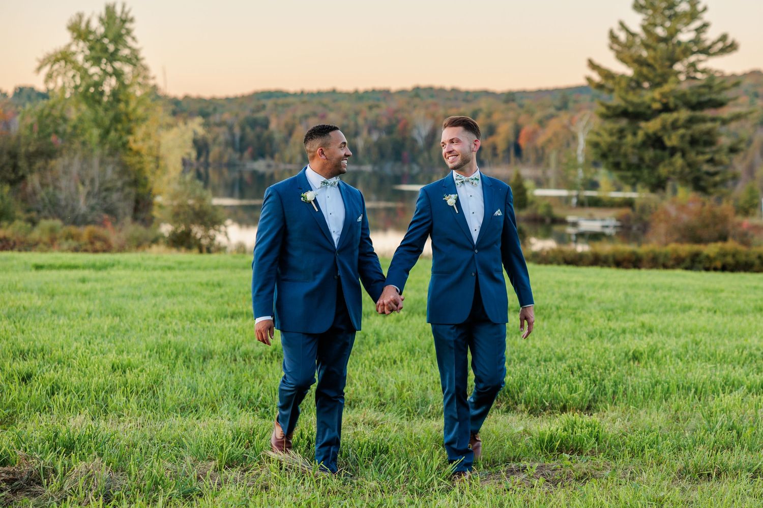 Couple shares emotional moment during outdoor wedding ceremony in grassy field at sunset.