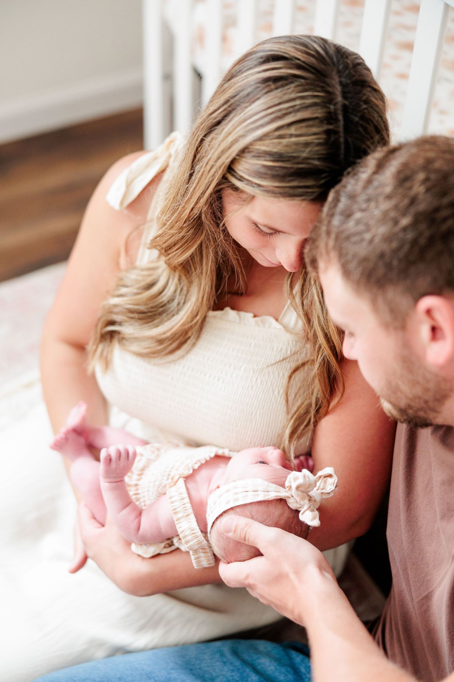 Close-up of loving parents gazing down at their newborn baby girl in a pink nursery.