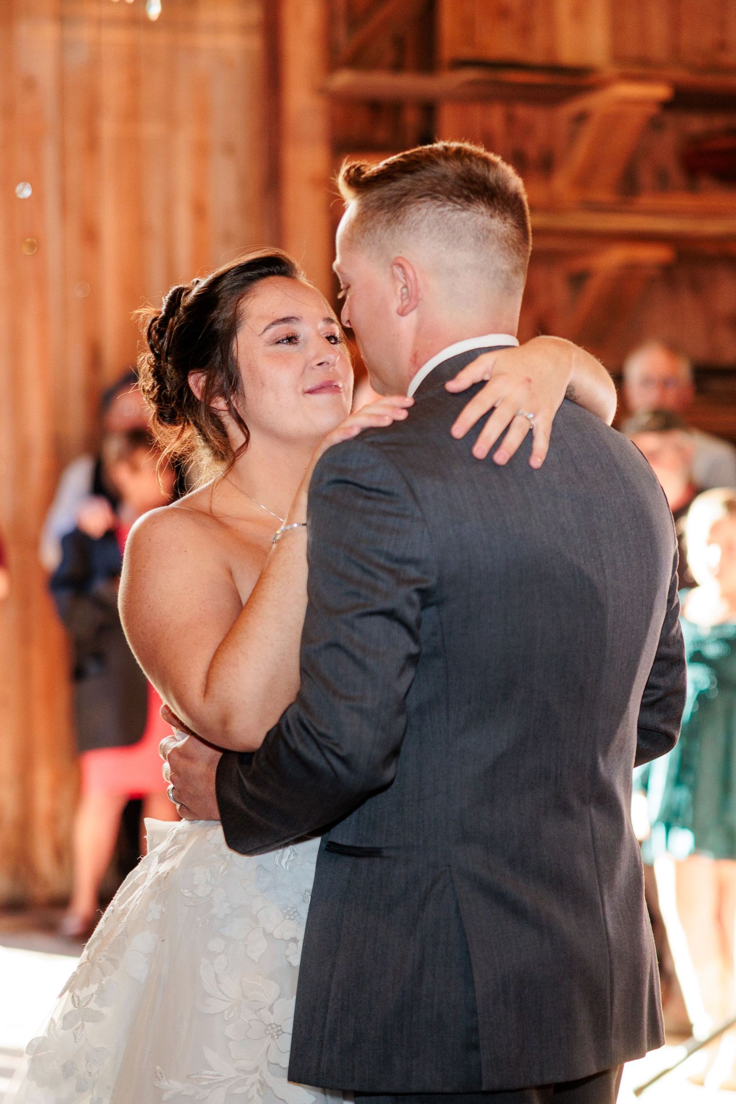 Bride and groom sharing their first dance inside a warmly lit rustic barn wedding venue.