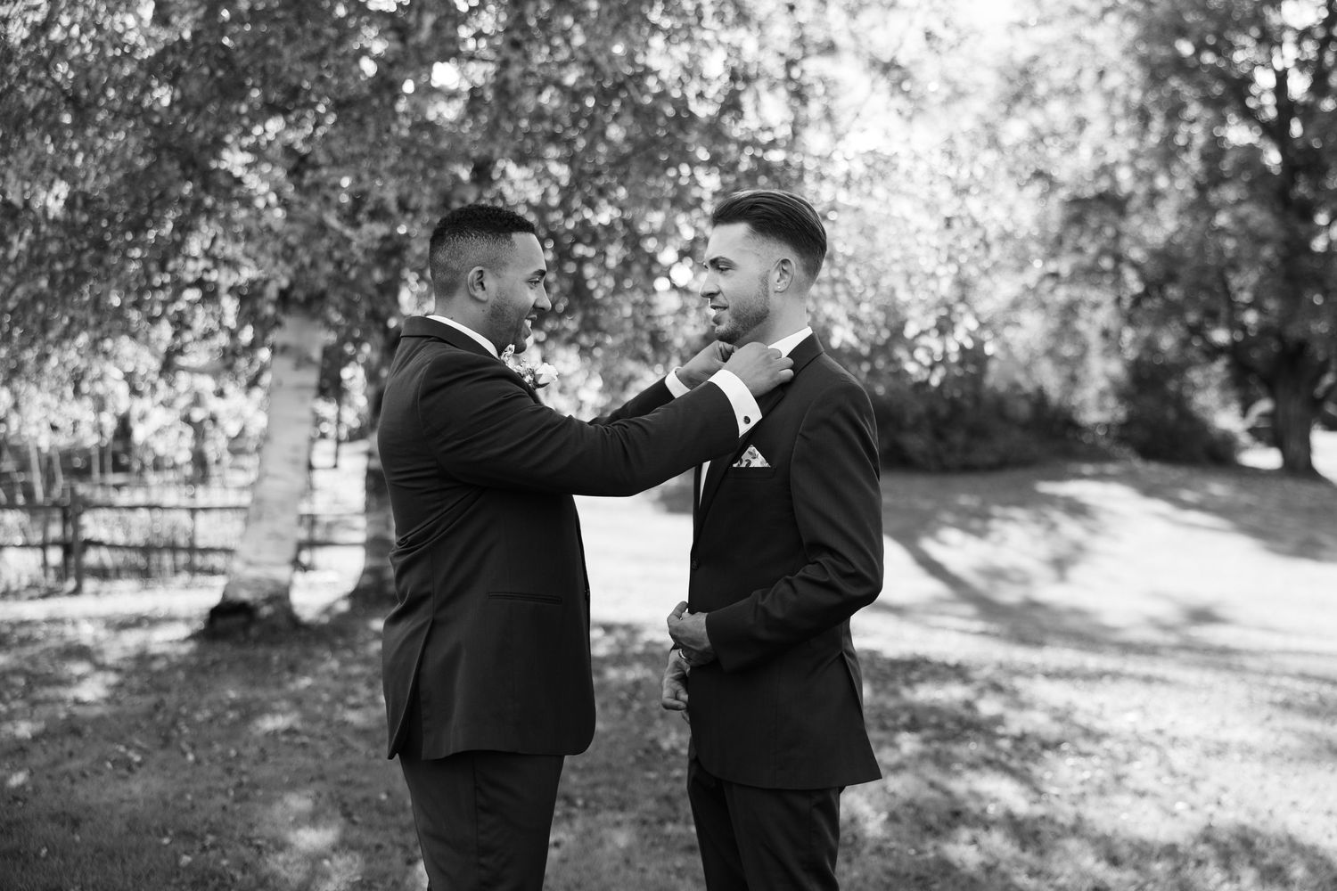 Couple in formal attire sharing intimate moments in a black and white outdoor photoshoot.
