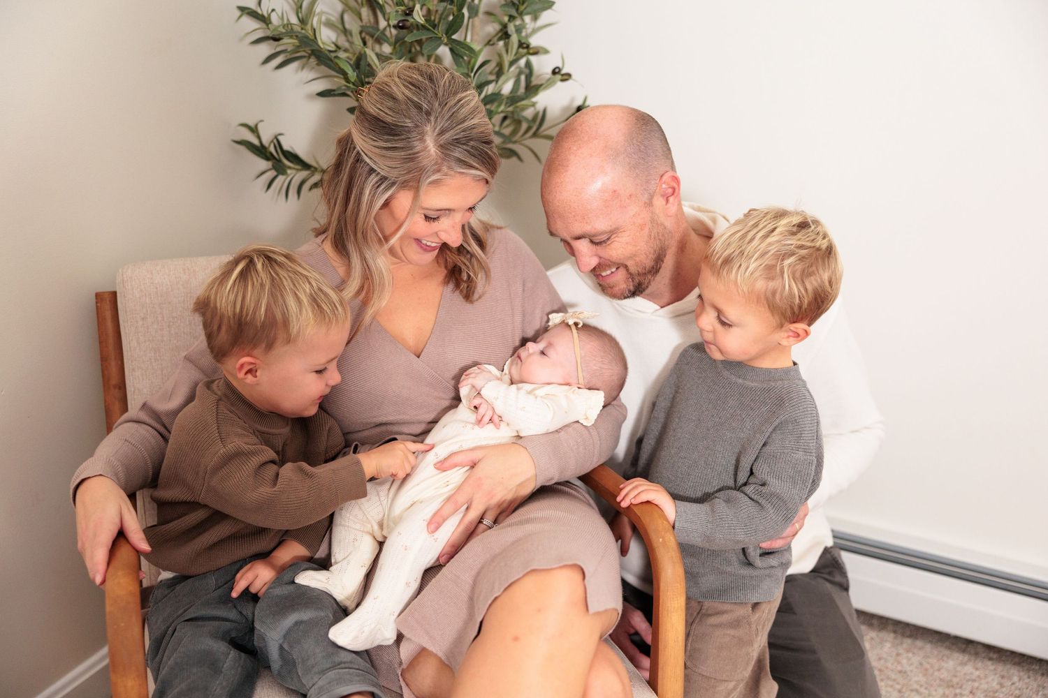 A family shares tender moments with their newborn baby in a series of intimate photographs against a neutral background.