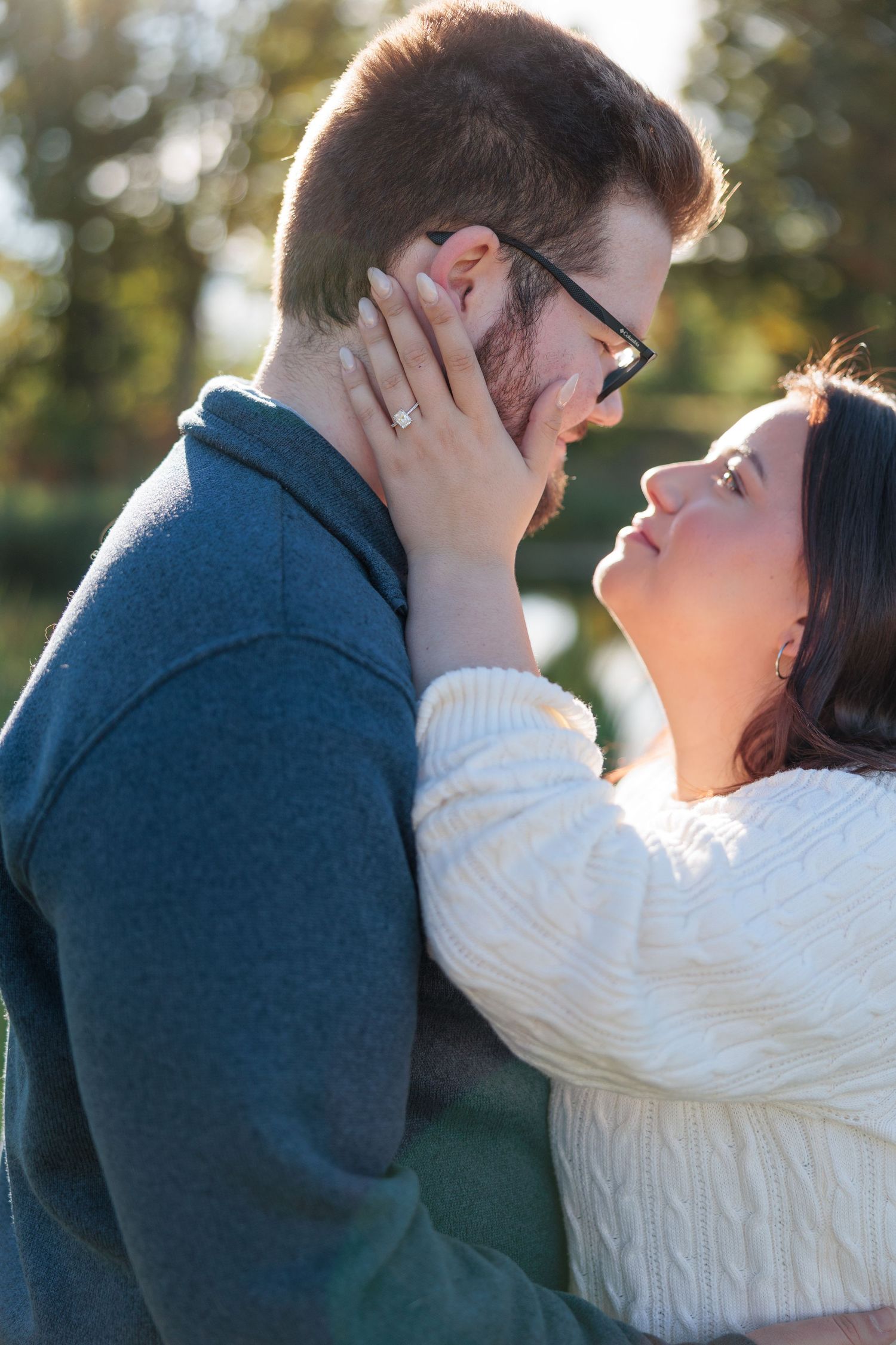 Romantic couple gazing into each others eyes as woman gently touches mans face outdoors.