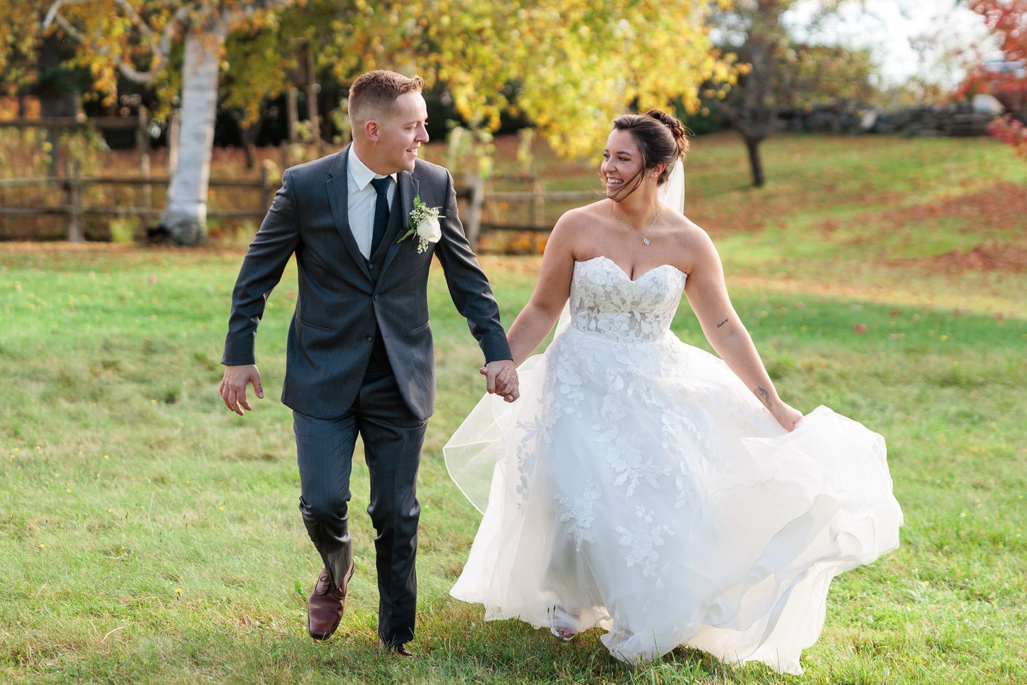 Joyful wedding party poses and plays in a field during golden autumn weather.
