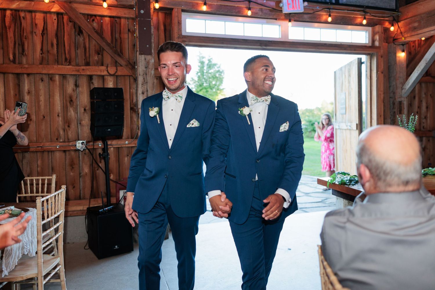 Wedding party celebrates inside rustic barn venue with warm lighting.