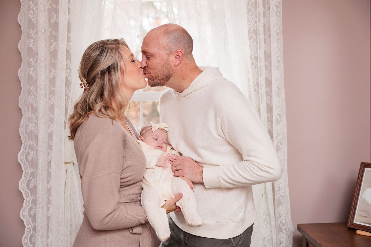 A couple in neutral colored clothing share intimate moments in a romantic indoor photoshoot series.