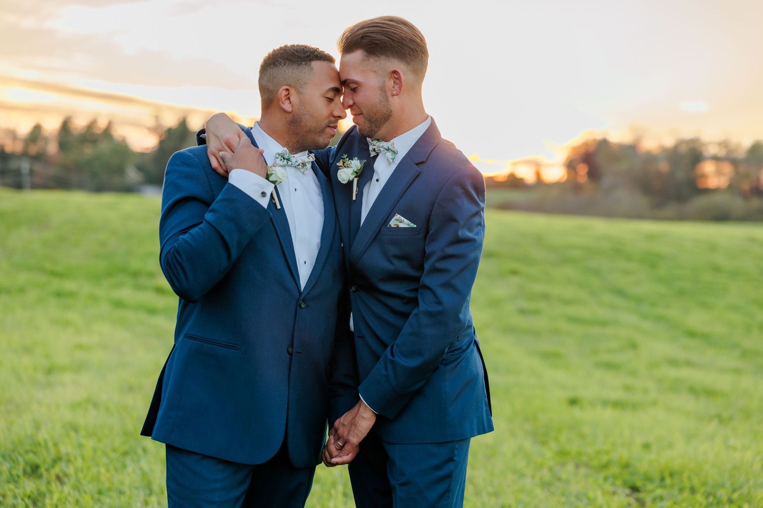 Romantic sunset portraits of a couple in navy suits sharing intimate moments in a field.