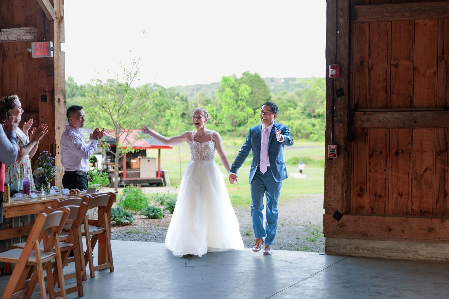 Newlyweds make grand entrance into rustic barn reception to guests applause.