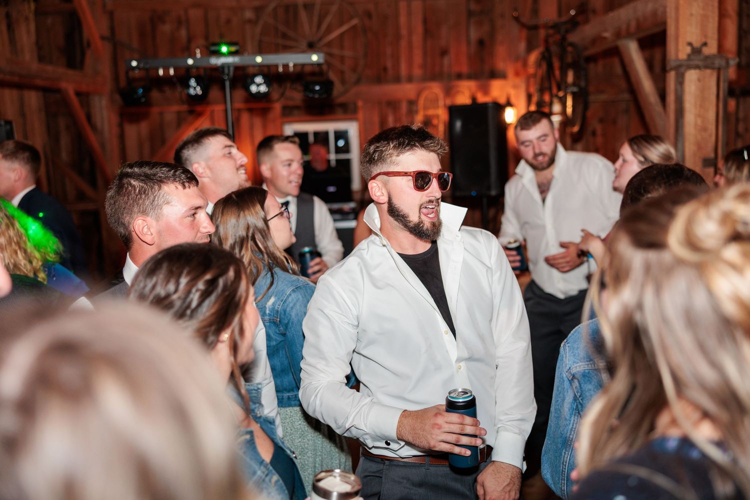 Wedding guests enjoying themselves on a dance floor inside a rustic barn venue.