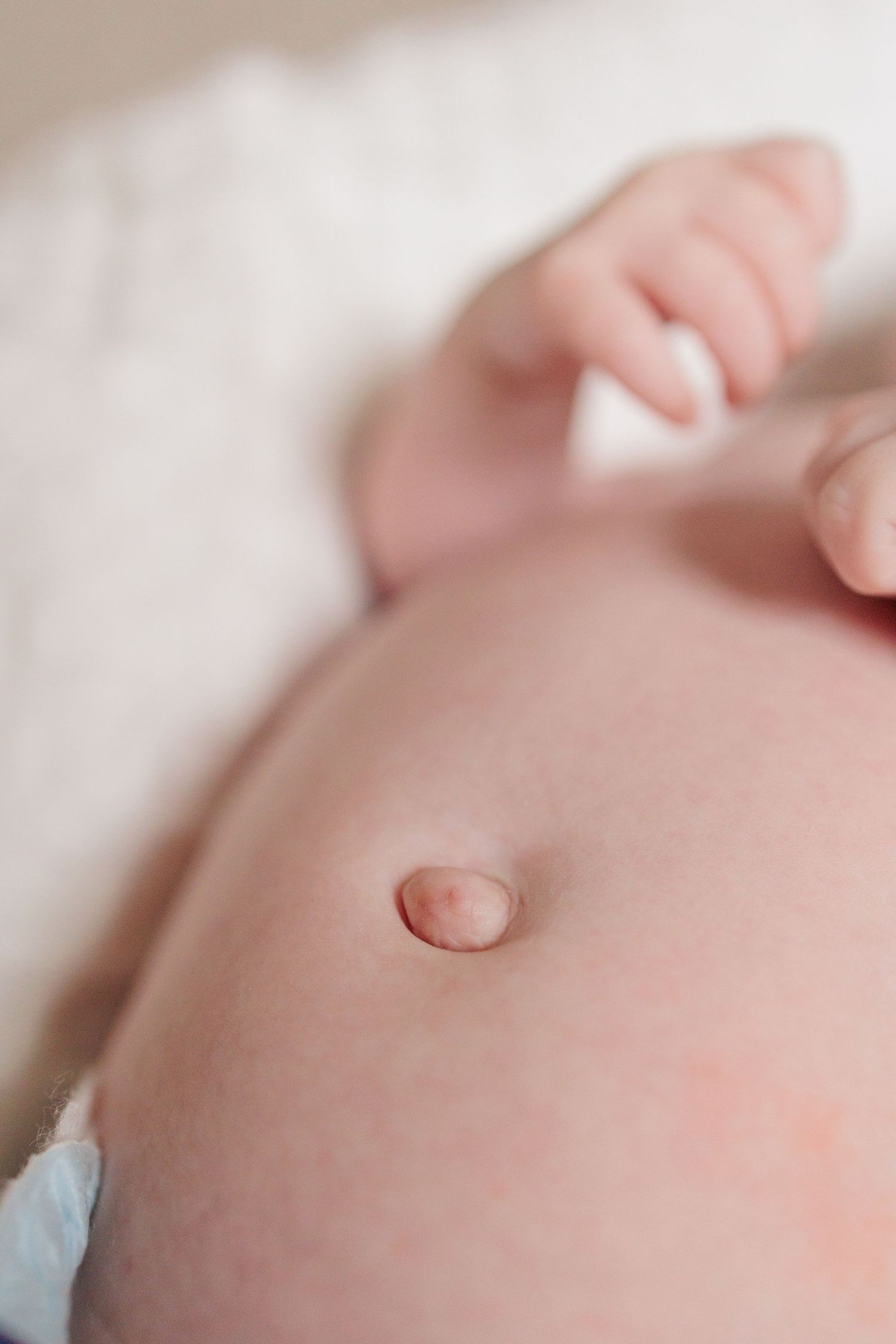 Close-up macro shot of a newborn baby's belly button against soft white fabric.