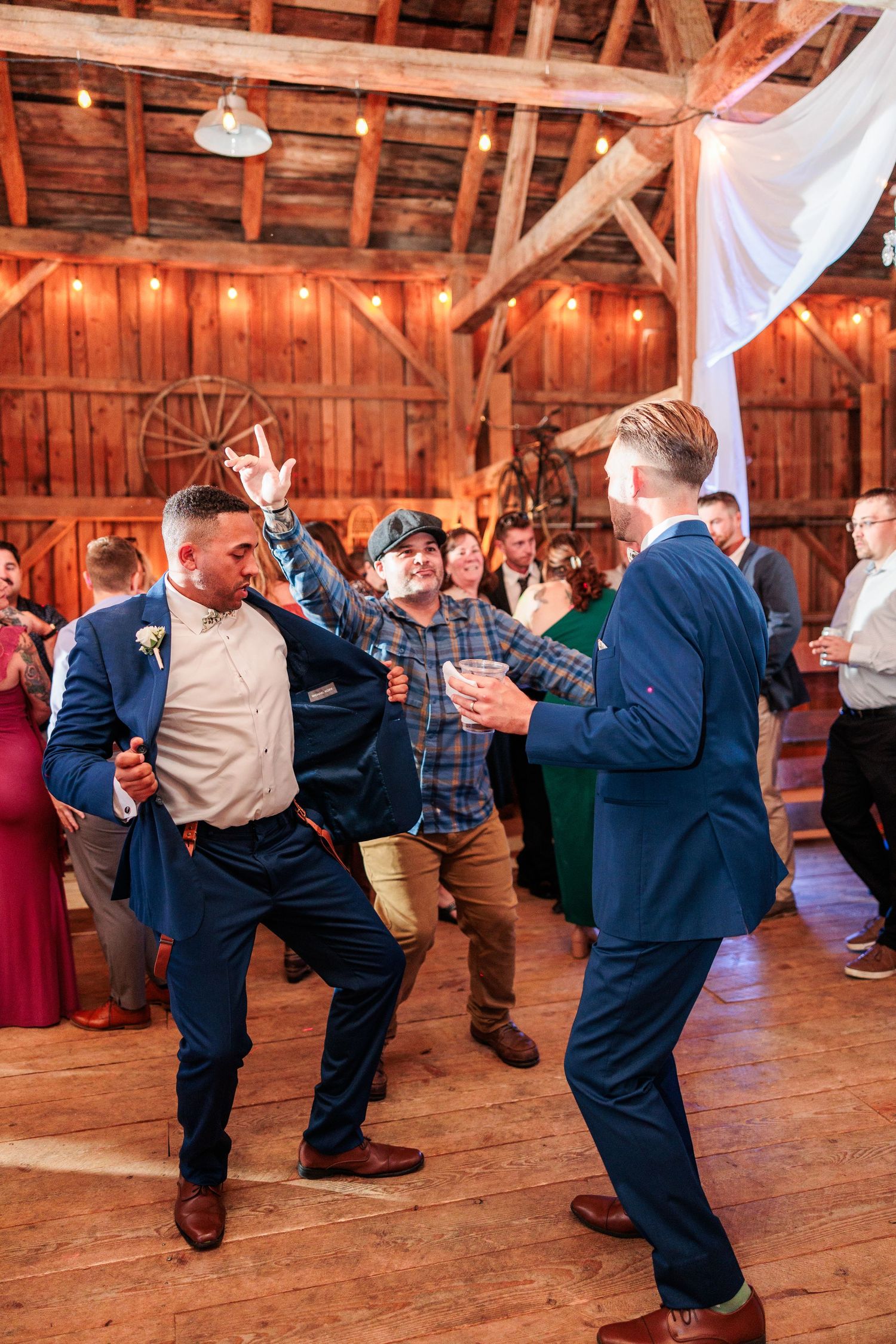 Dancers performing synchronized moves on a rustic wooden dance floor at a barn event.