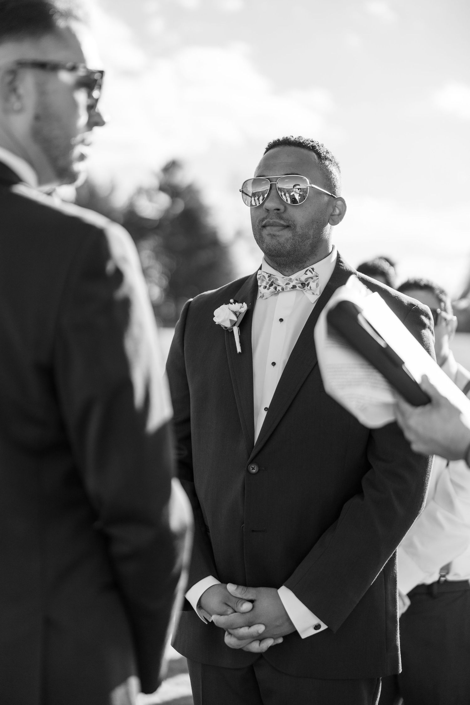 Wedding party members in formal attire share laughs during outdoor celebration.
