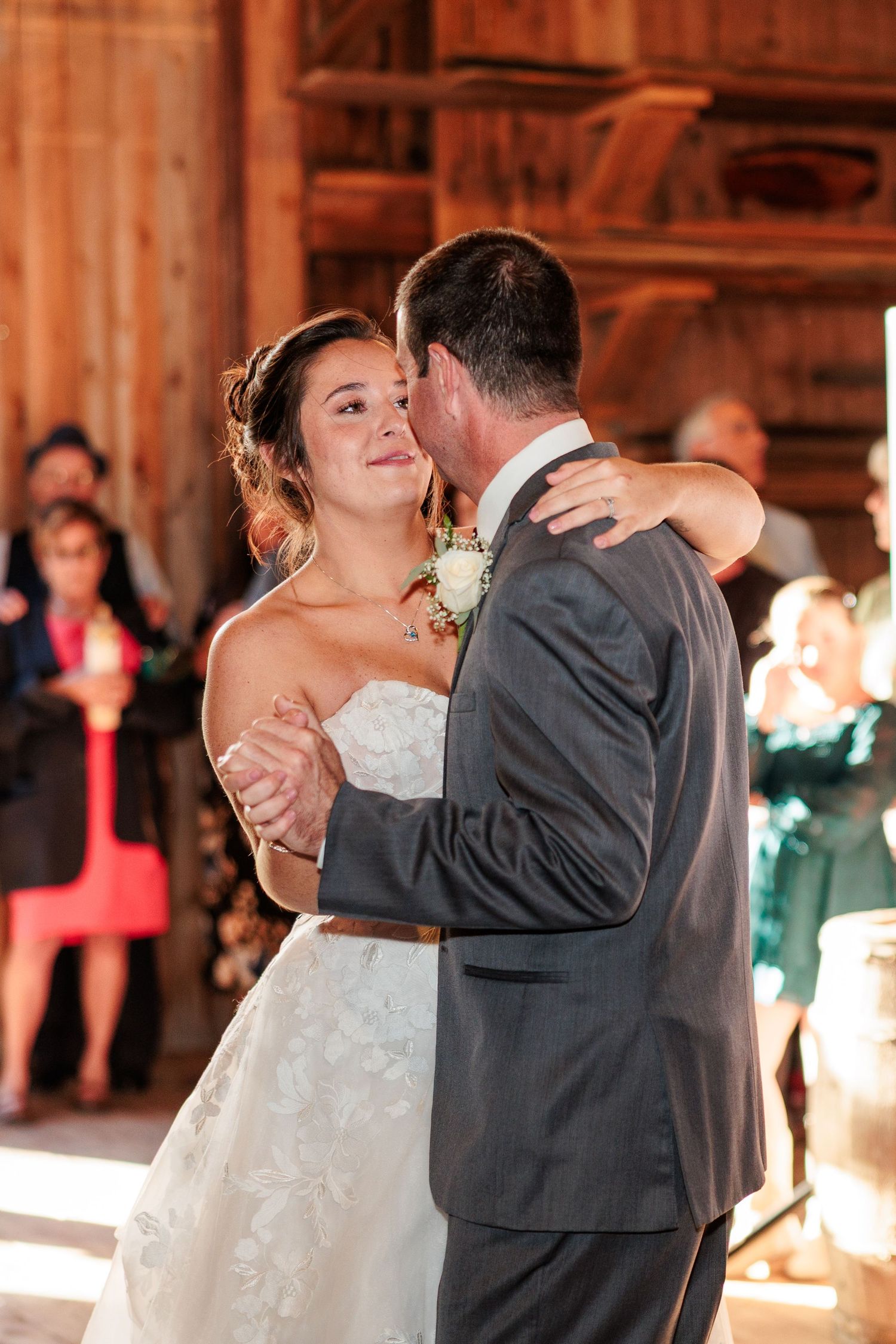 Couple sharing intimate dance moment in warmly lit rustic barn setting.