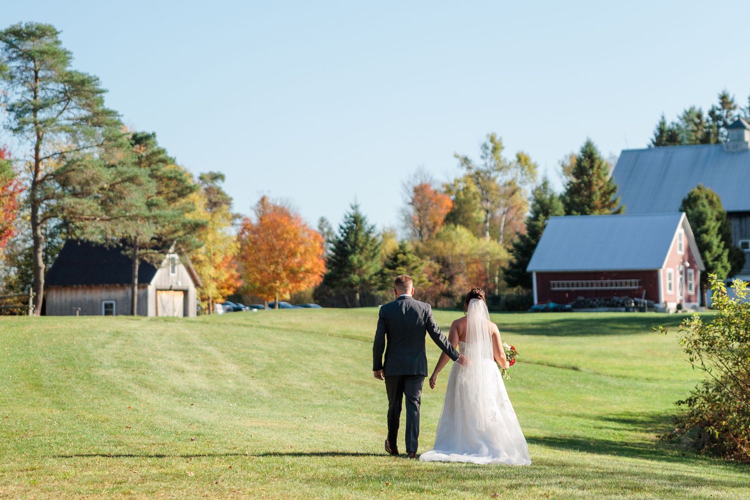 A couple walks through a scenic autumn golf course during a wedding photo session on a sunny day.