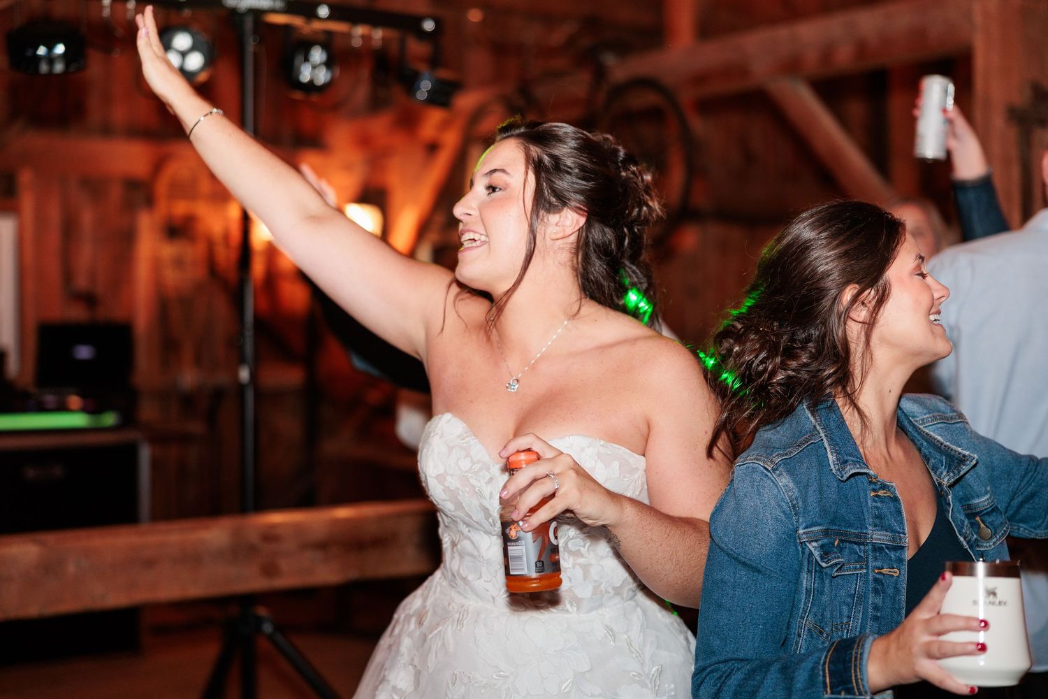 Bride enjoying the dance floor festivities at a rustic barn wedding reception.
