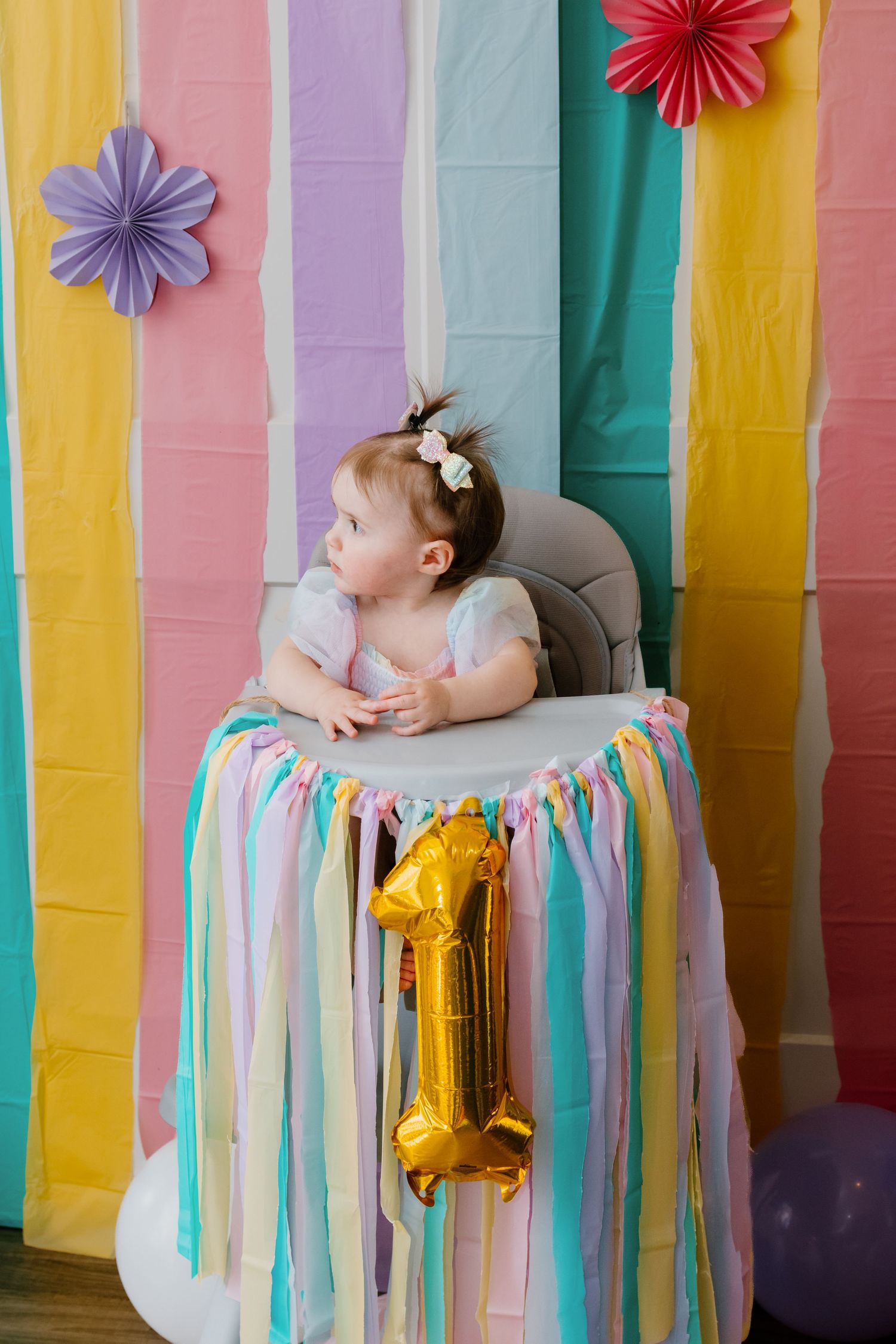 First birthday milestone session with colorful streamers and balloons.