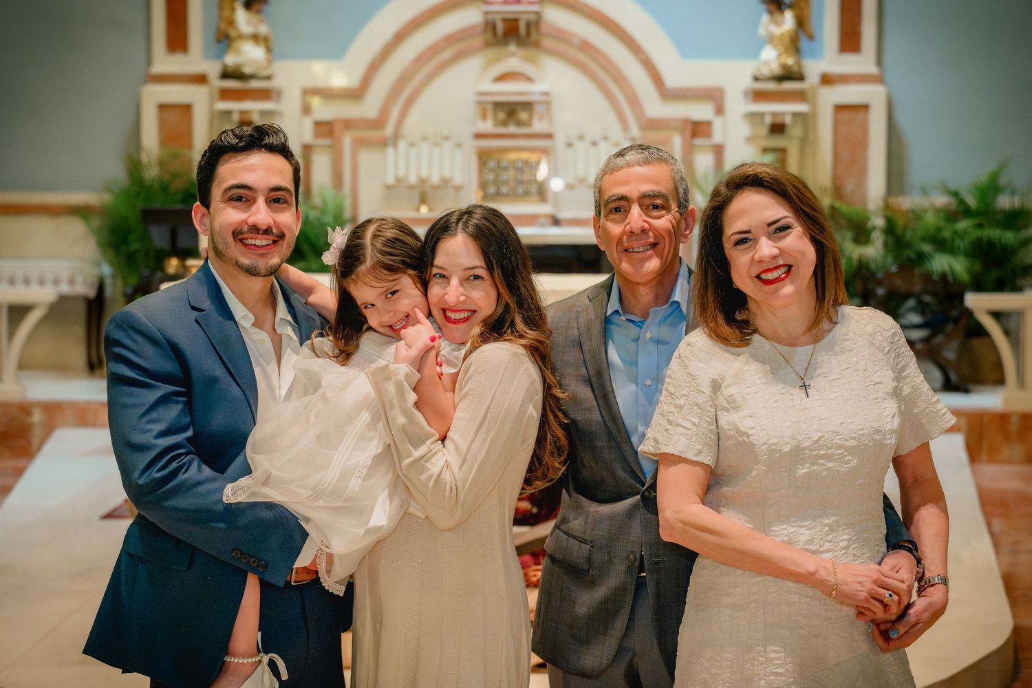 Family gathering inside a beautiful church with arched architecture and decorative altar in the background.