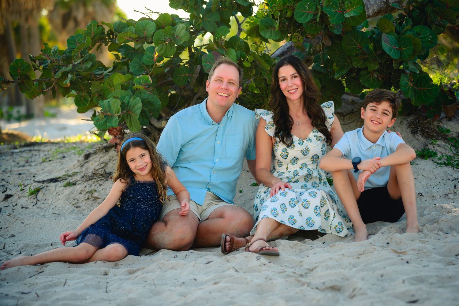 Group relaxing together on sandy beach during golden hour photoshoot session.