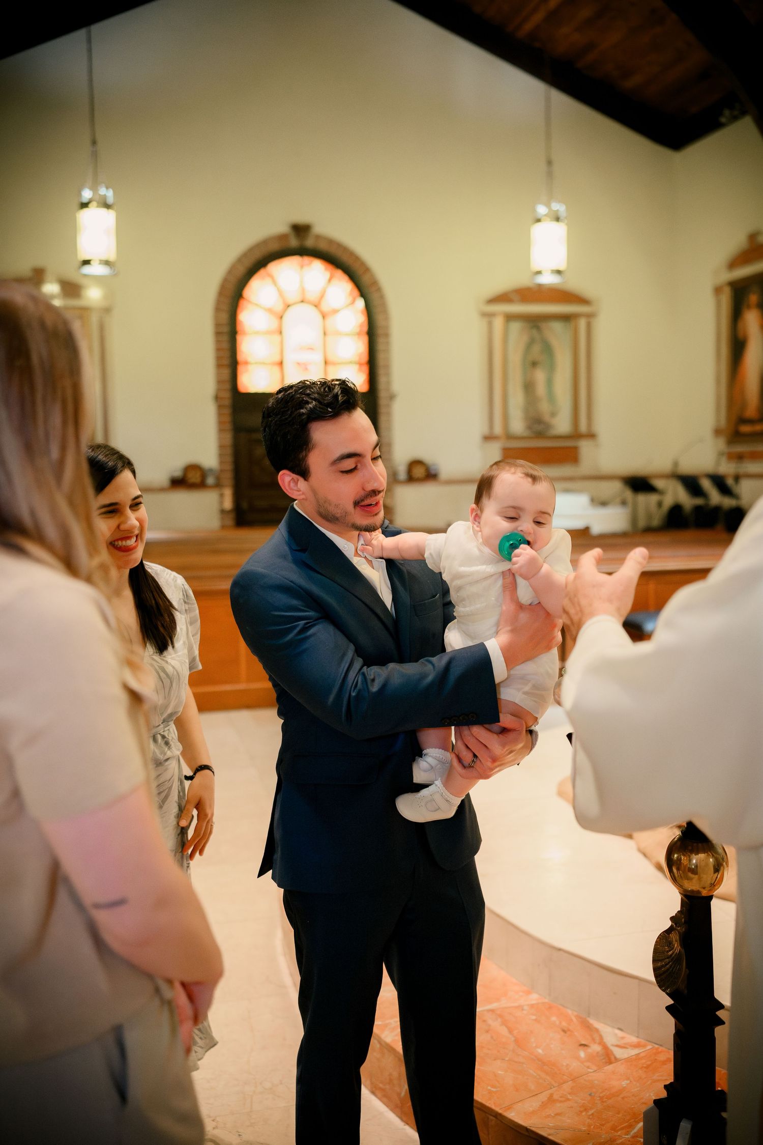 A couple performs a romantic dip dance move together in a church setting with pendant lights hanging above.