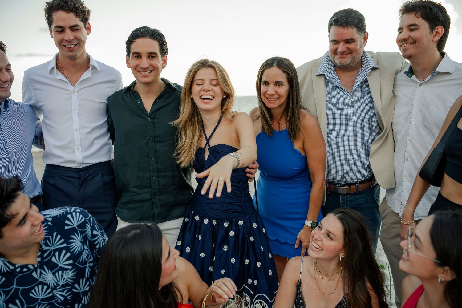Group of young adults smiling and laughing together at an outdoor social gathering in summer attire.