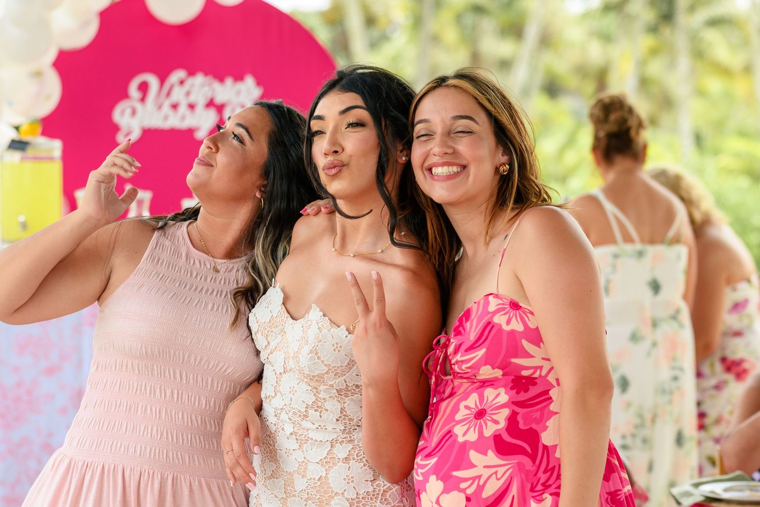 A group of bridesmaids in pink dresses pose together during an outdoor wedding celebration.