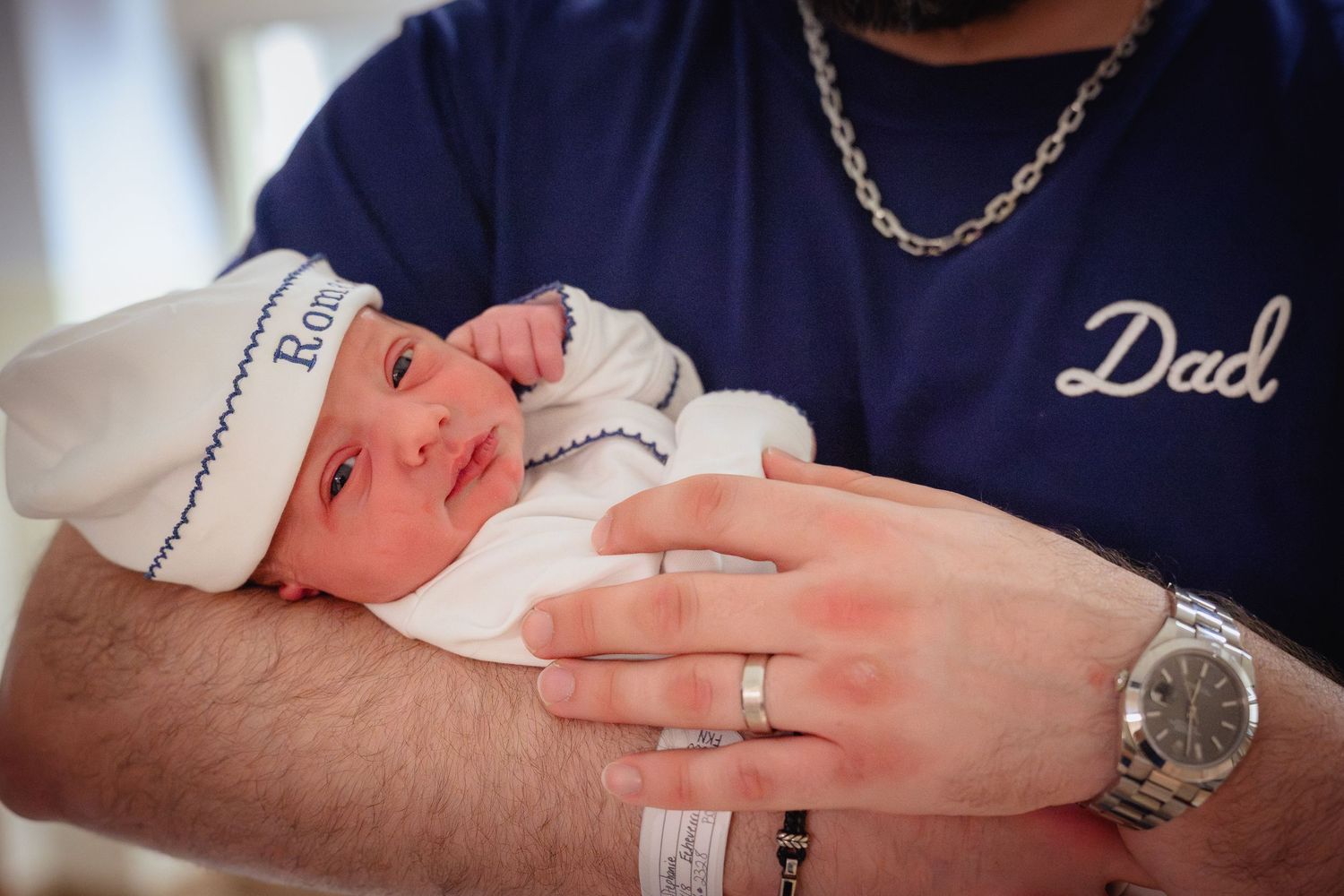 A series of photos showing a newborn baby's tiny feet and hands being held by parents wearing navy blue shirts.