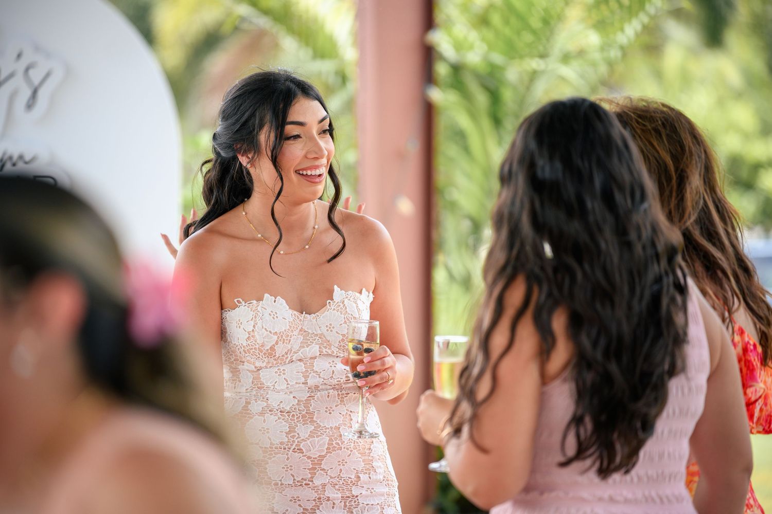 A bride in a white lace wedding dress laughs joyfully during a wedding celebration.