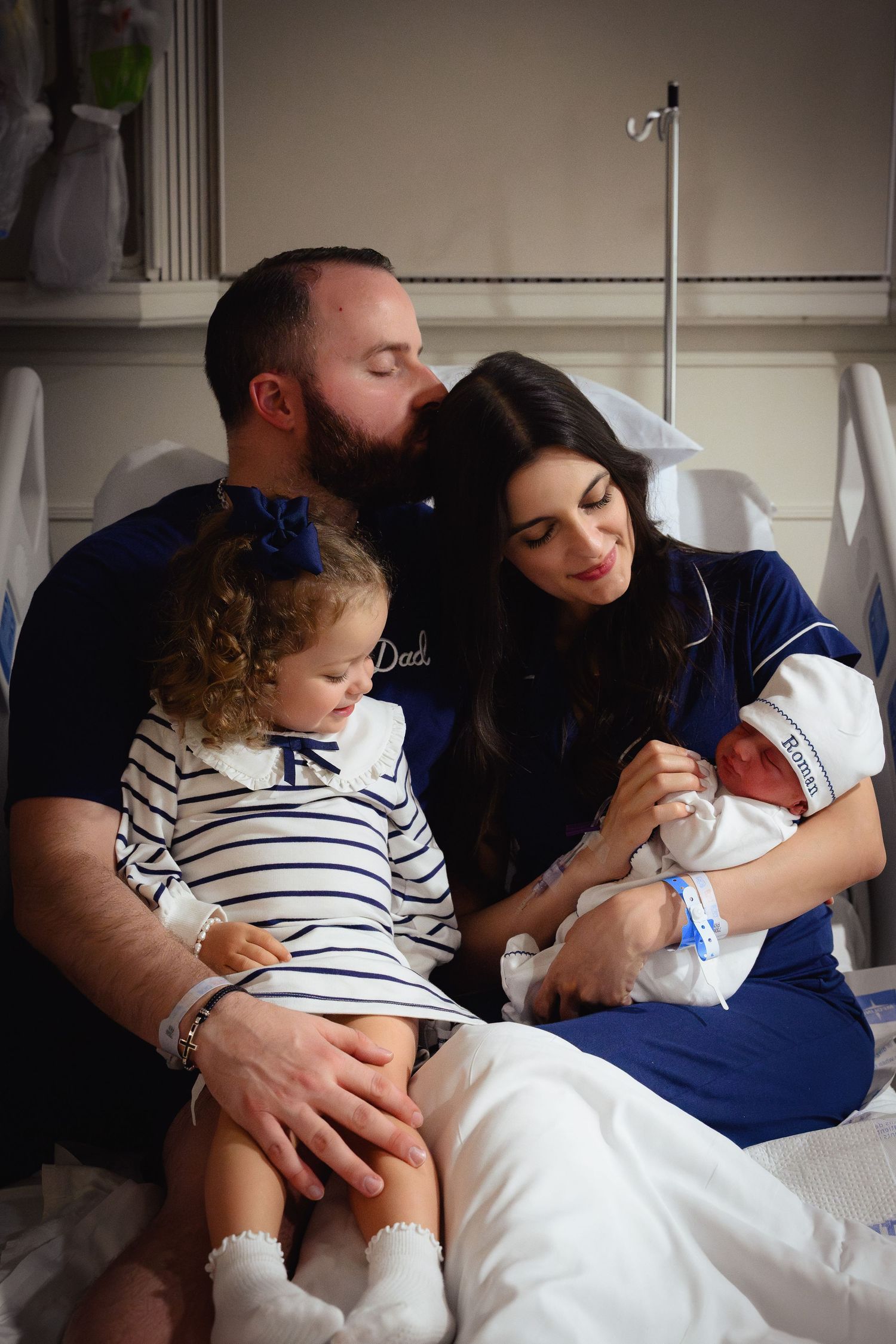 Family resting together on a white bed in a series of intimate candid moments.