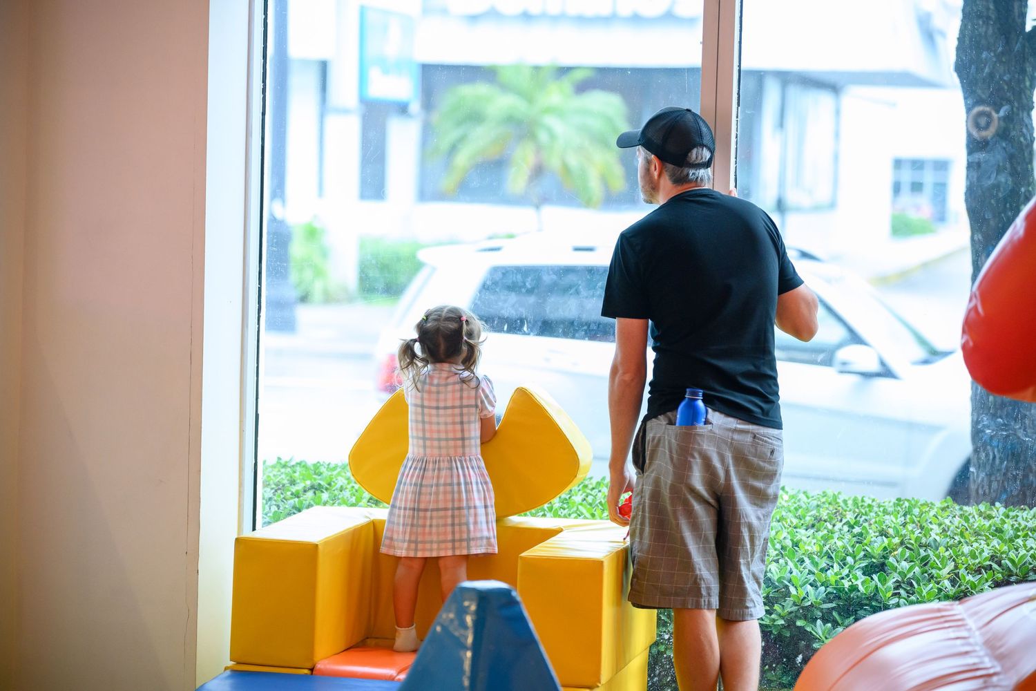 Children play at an indoor playground with colorful yellow and orange play structures and climbing equipment.