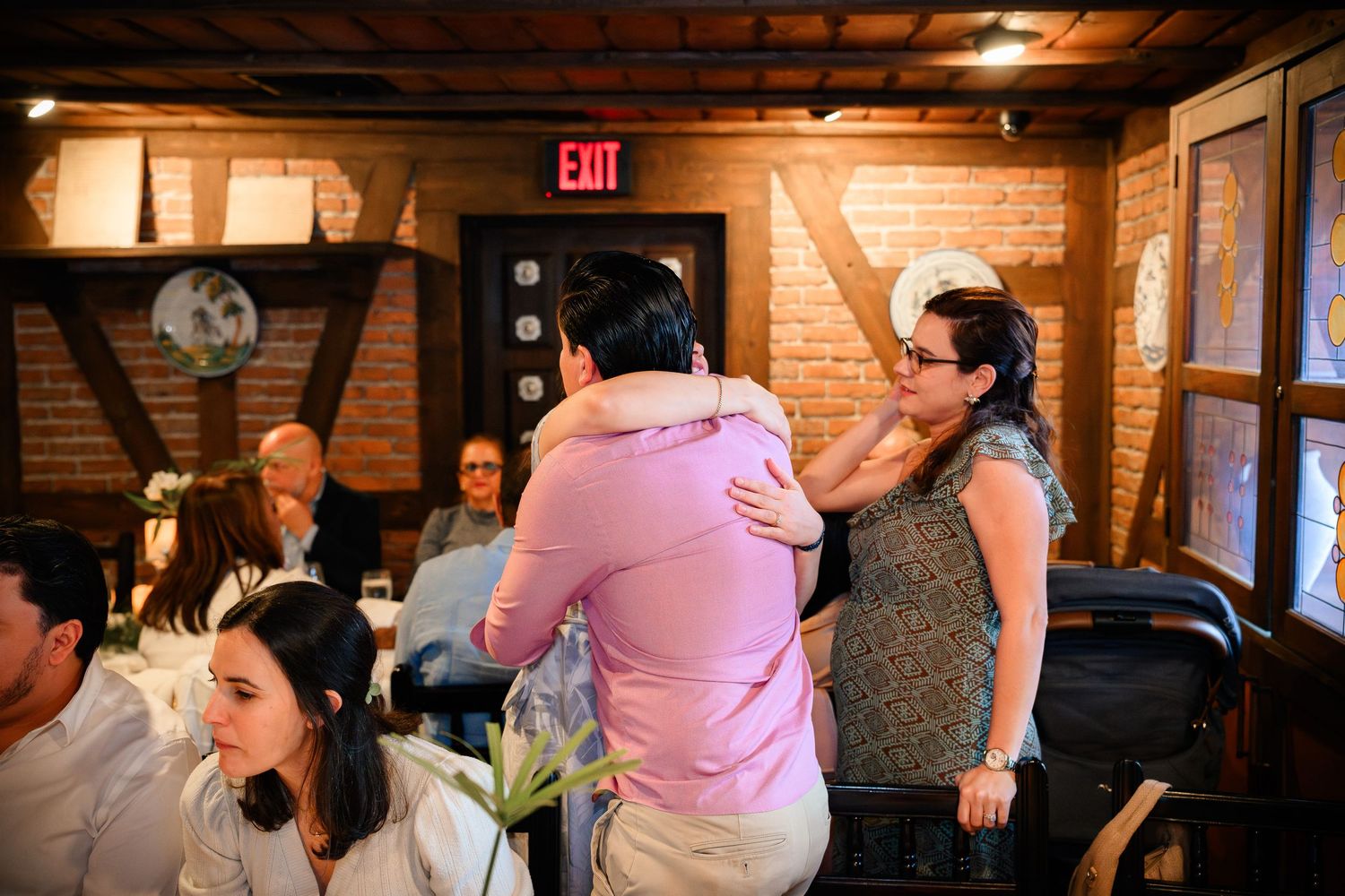 A group of people dancing together in a rustic venue with exposed brick walls and warm lighting.