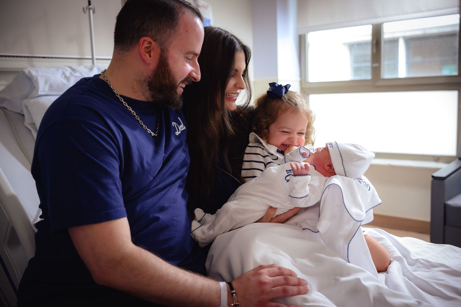 New parents with toddler meet their newborn baby for the first time in hospital room.