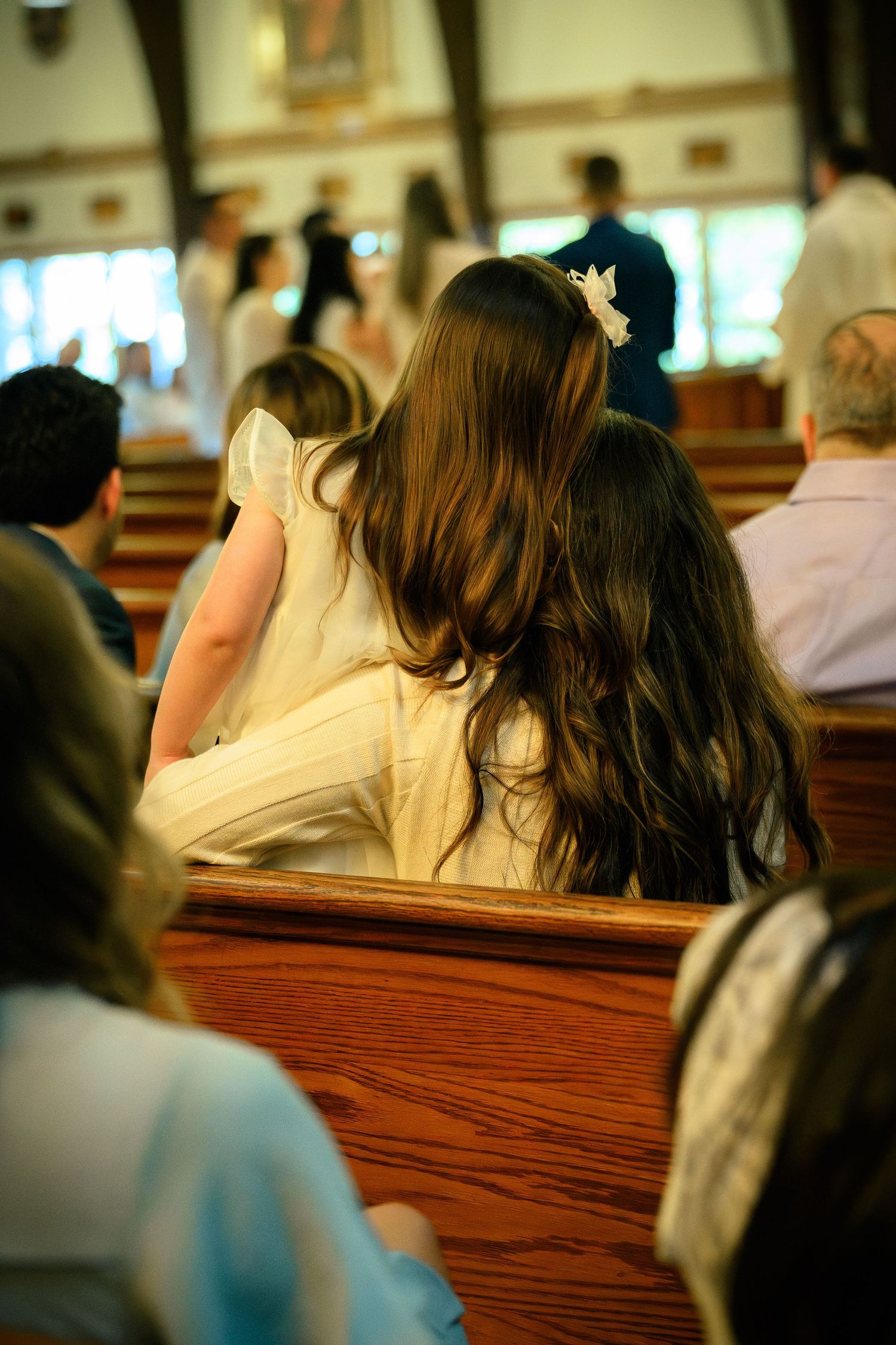 A candid moment between a mother and daughter awaiting the ceremony of a Catholic baptism at St. Raymond, Coral Gables, Miami, FL