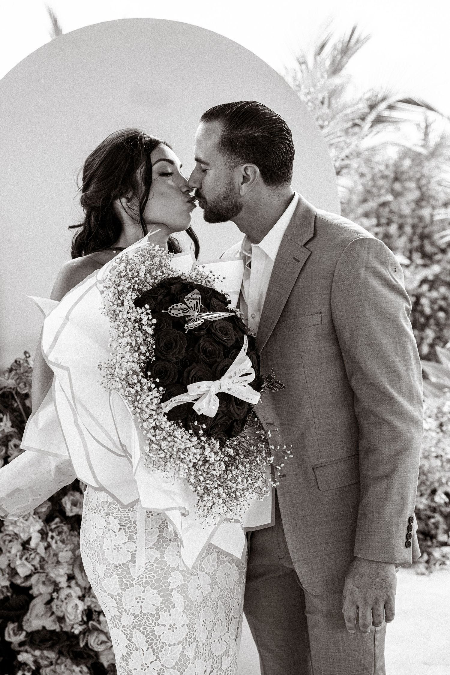 A romantic black and white wedding photo series showing tender moments between a couple in formal attire.
