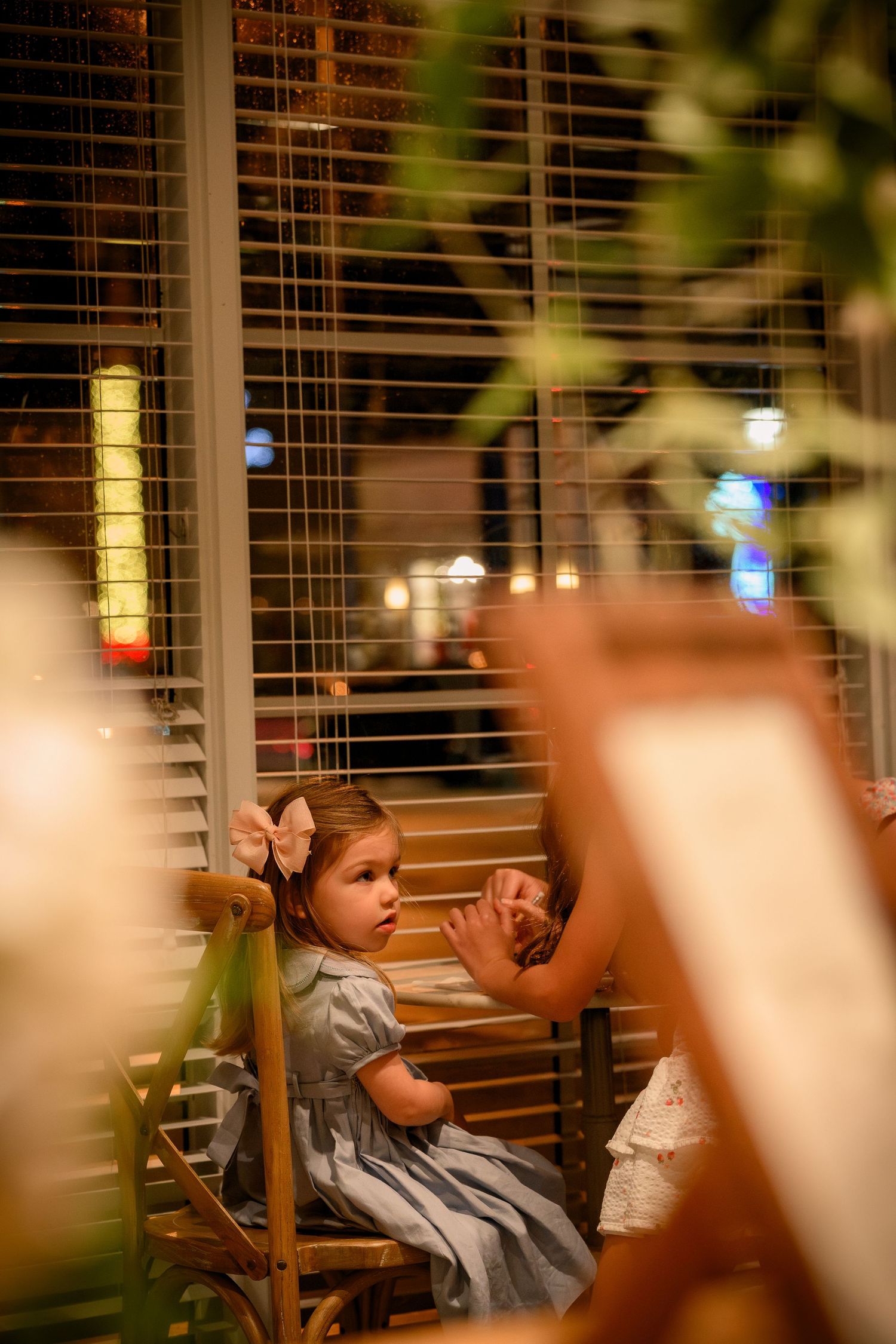 A dimly lit interior scene with window blinds and soft lighting creates a warm, atmospheric ambiance.