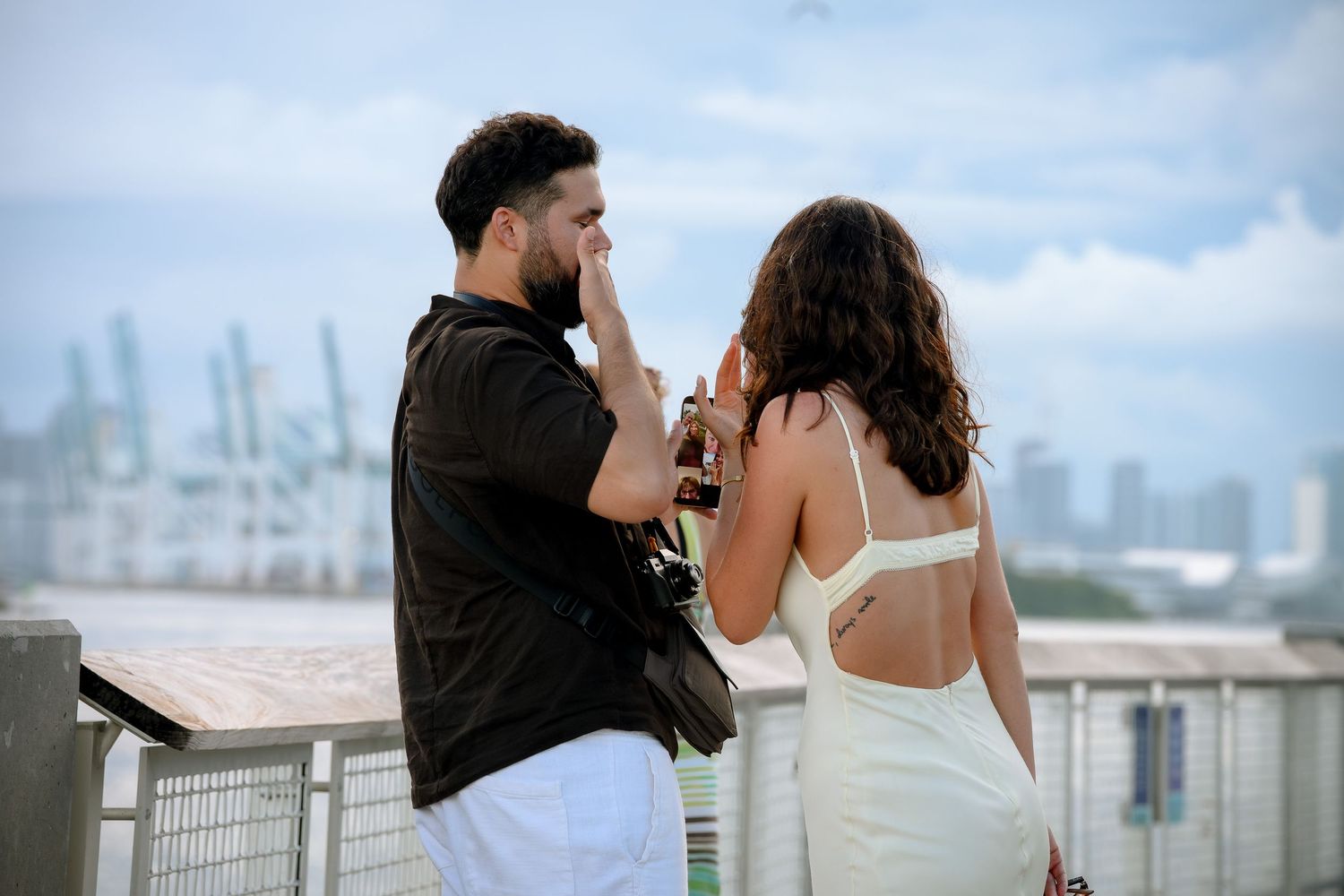 Couple sharing an intimate moment on a rooftop overlooking a city skyline on a cloudy day.