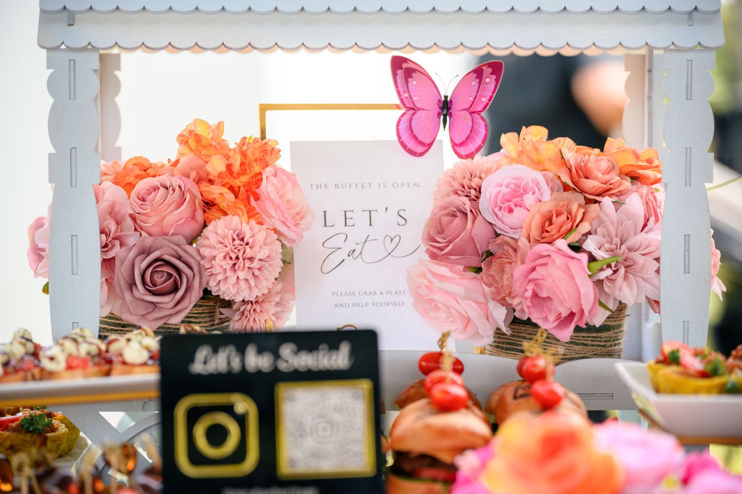 Pink and coral floral arrangements with roses decorate an elegant wedding reception table setting.