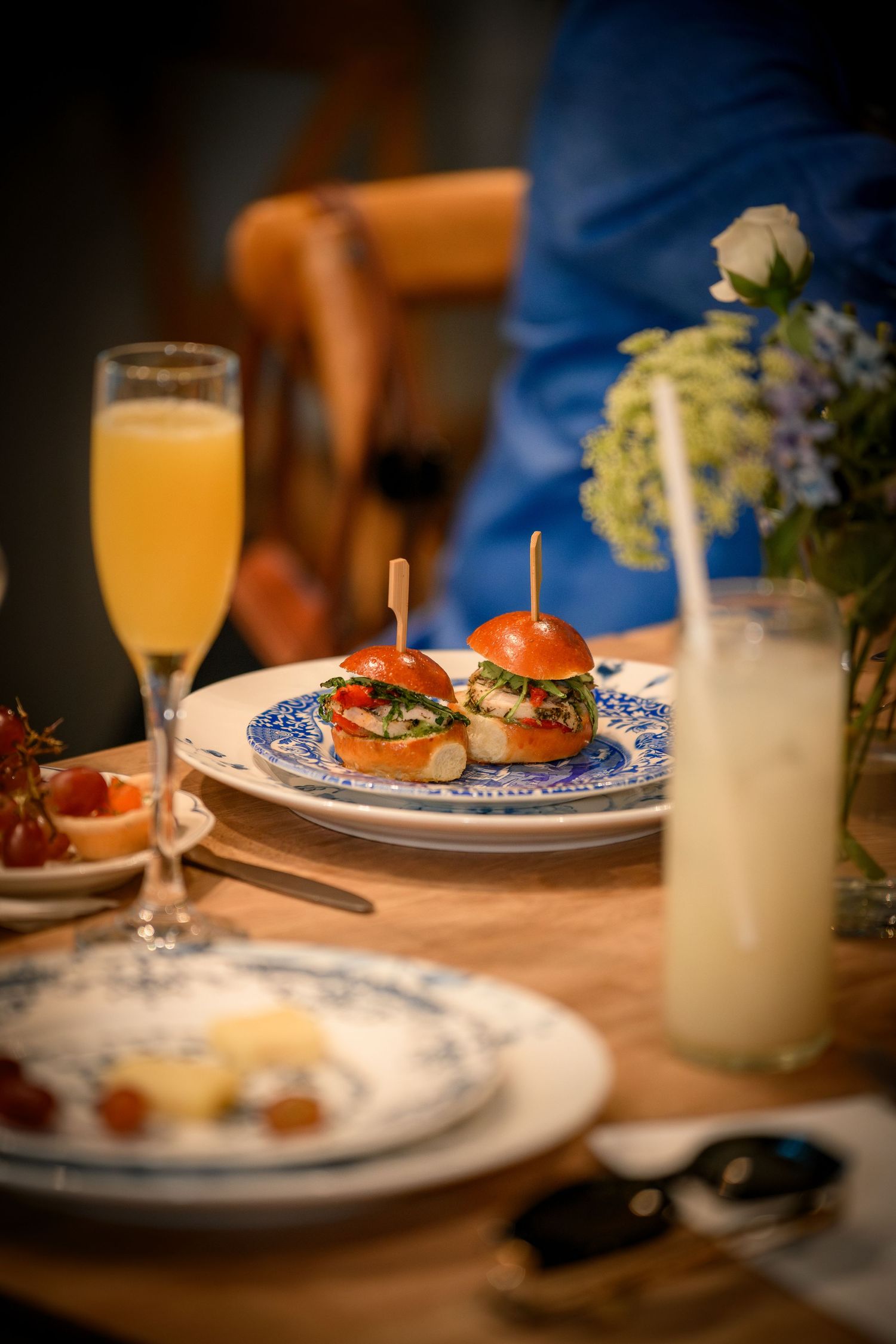 Gourmet sliders on blue and white plates served with mimosas and fresh juice at a bridal brunch.