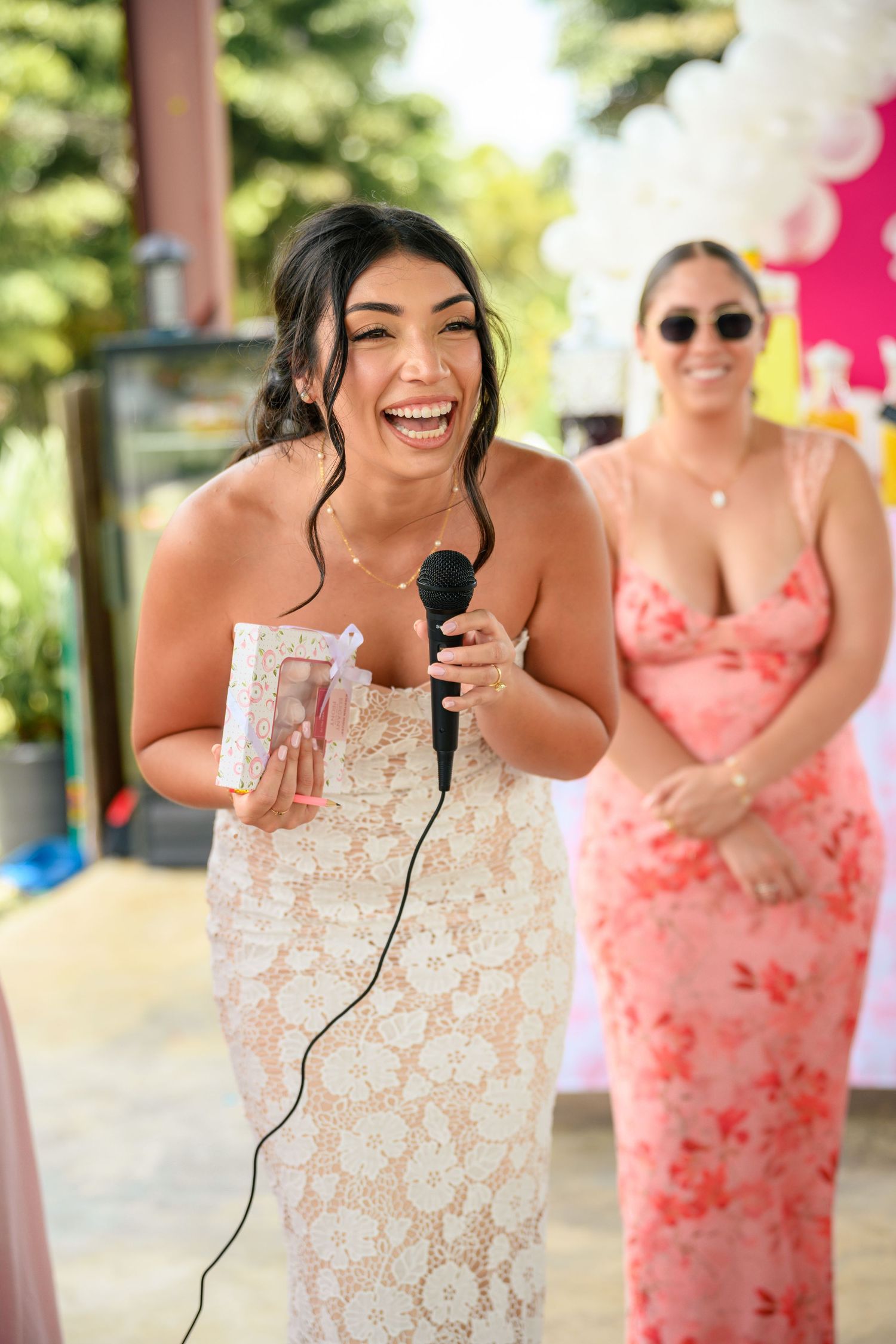A series of photos showing someone in a white lace dress laughing while holding a microphone at an outdoor event.