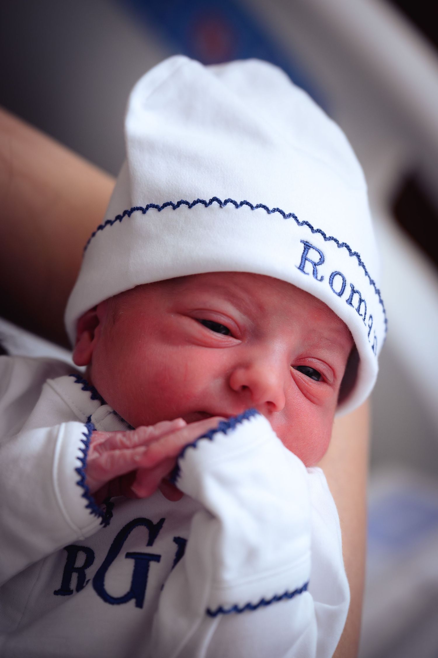 A newborn baby wearing a white knit cap with blue trim is shown in a series of close-up shots.