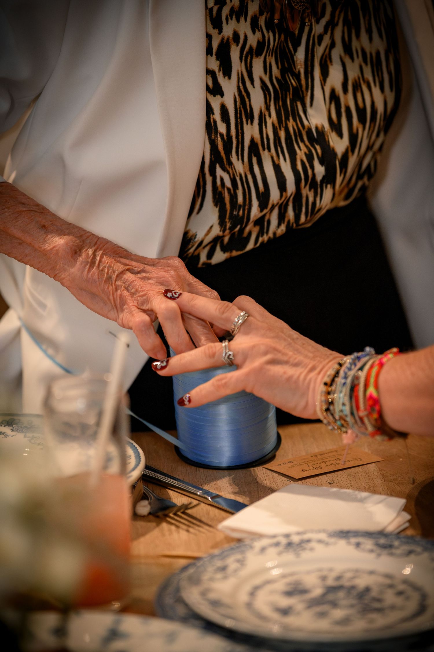 Close-up of two women holding hands at a elegantly set table during a special celebration event.