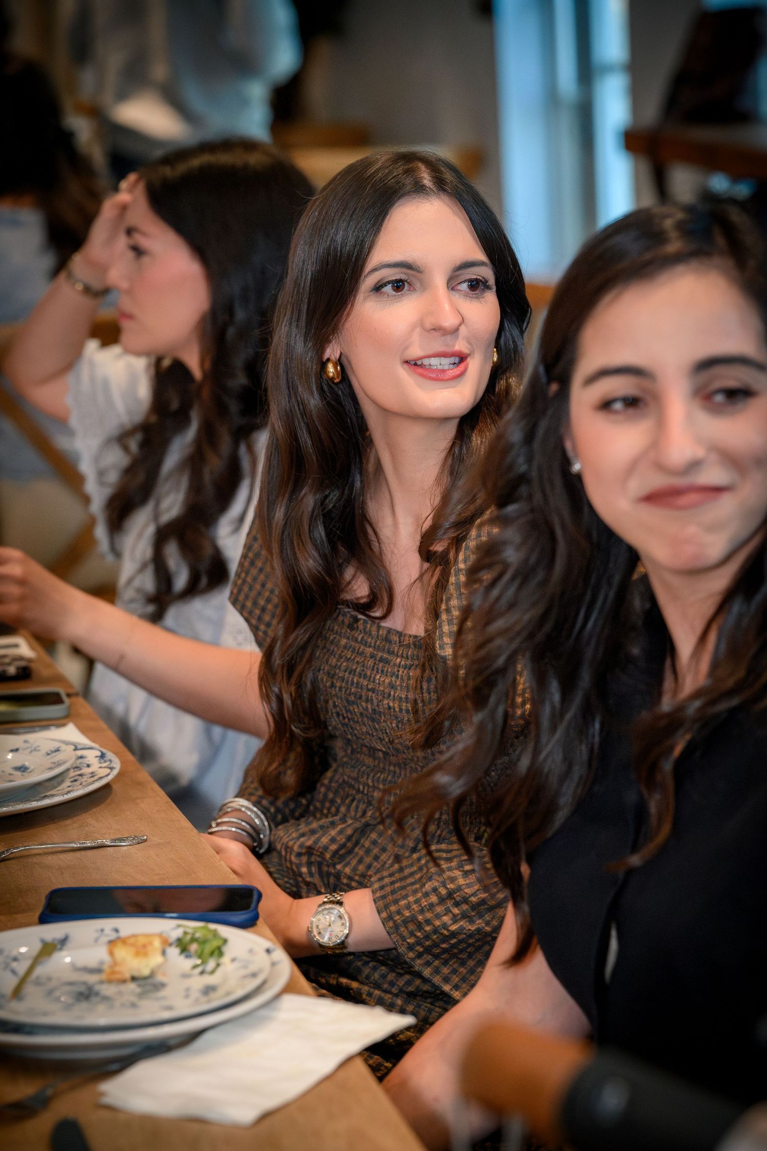 Friends enjoying a casual meal together at a restaurant table while engaged in lively conversation.