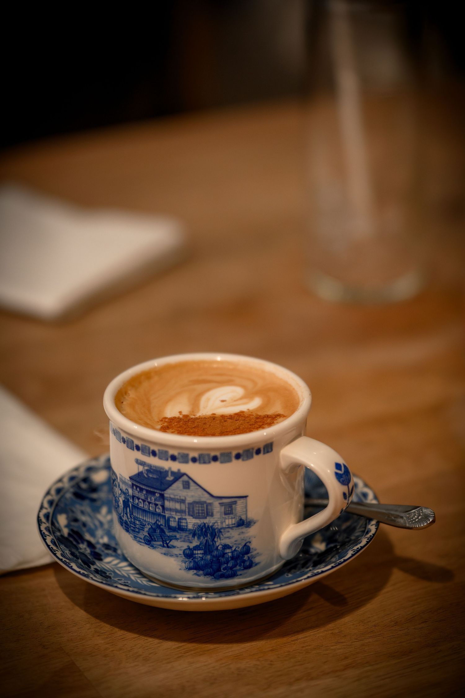 Cappuccino served in a traditional blue and white china teacup with saucer on a wooden table.