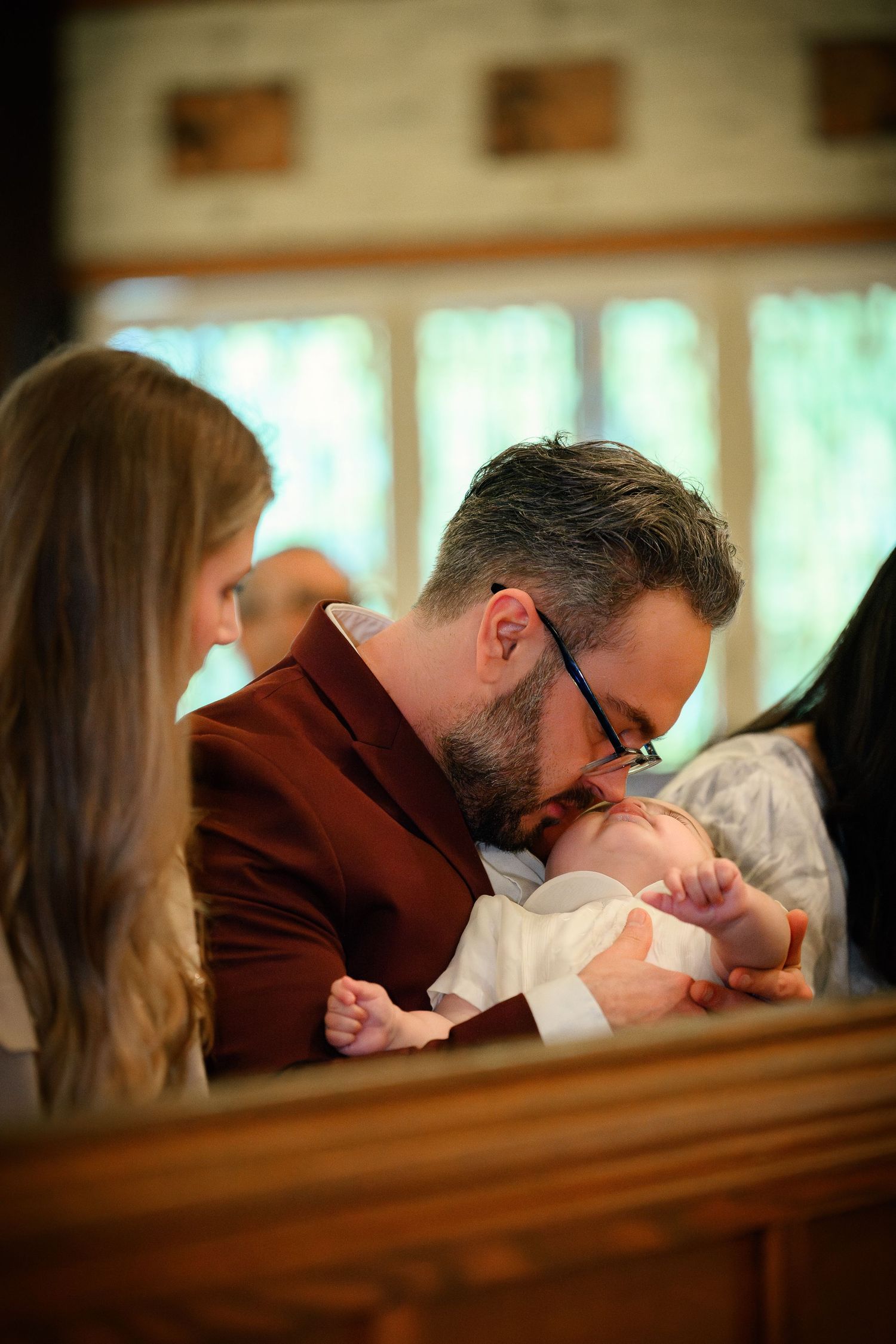 A candid moment between a father and his baby during the ceremony of a Catholic baptism at St. Raymond, Coral Gables, Miami, FL