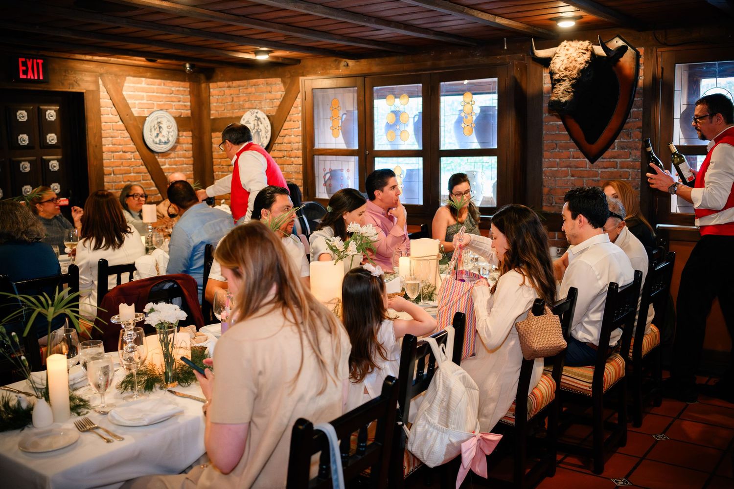 Wedding reception guests gather in a rustic wood-paneled restaurant venue for dinner and celebration.