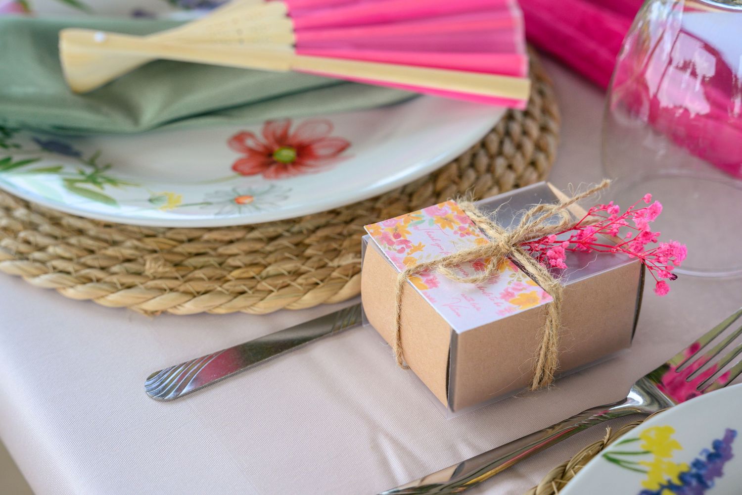 Pink and yellow pencils arranged with kraft paper gift boxes and floral decorations on a rustic table setting.