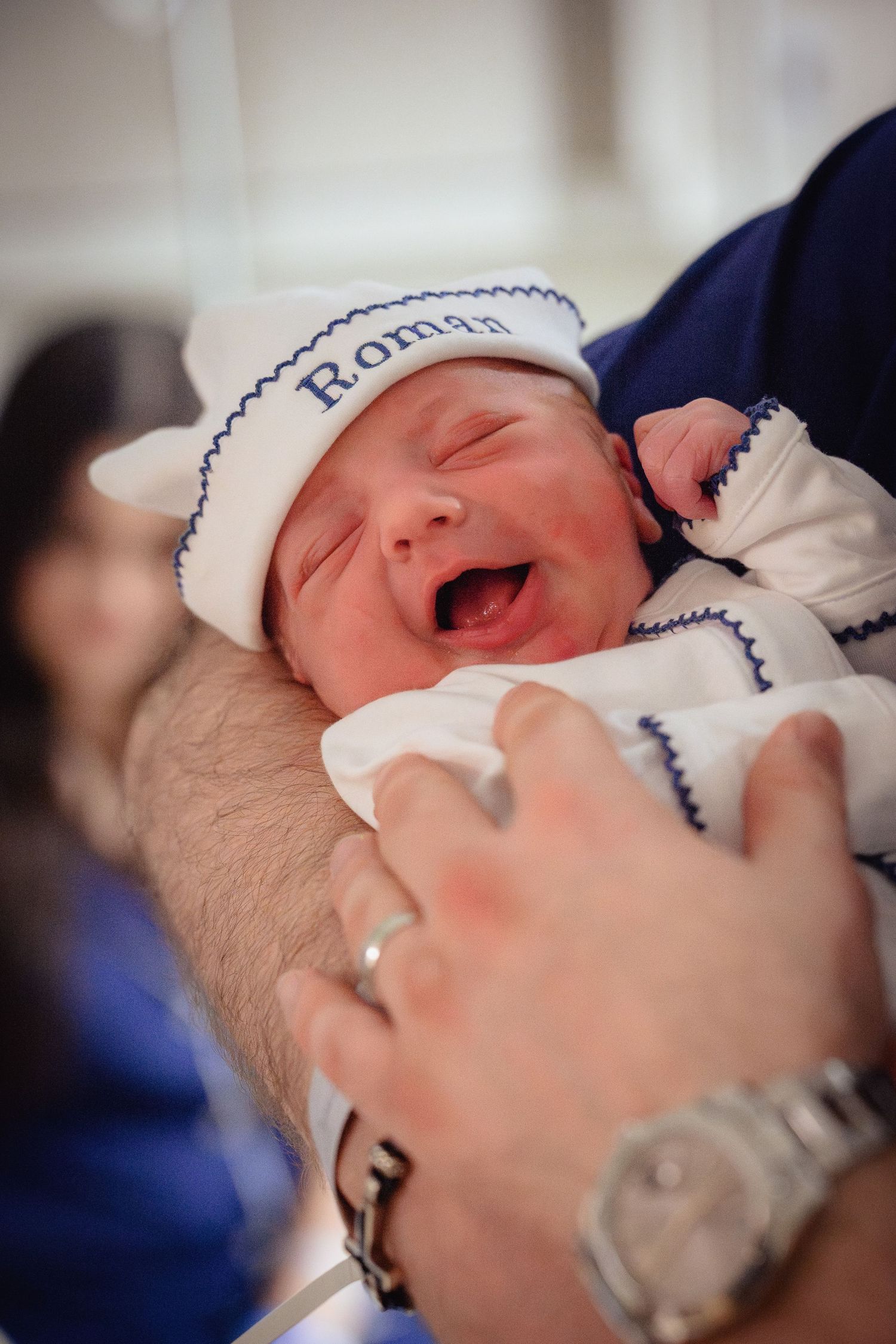 A series of close-up photos showing a newborn baby wearing a white knit cap with blue trim in various sleeping poses.