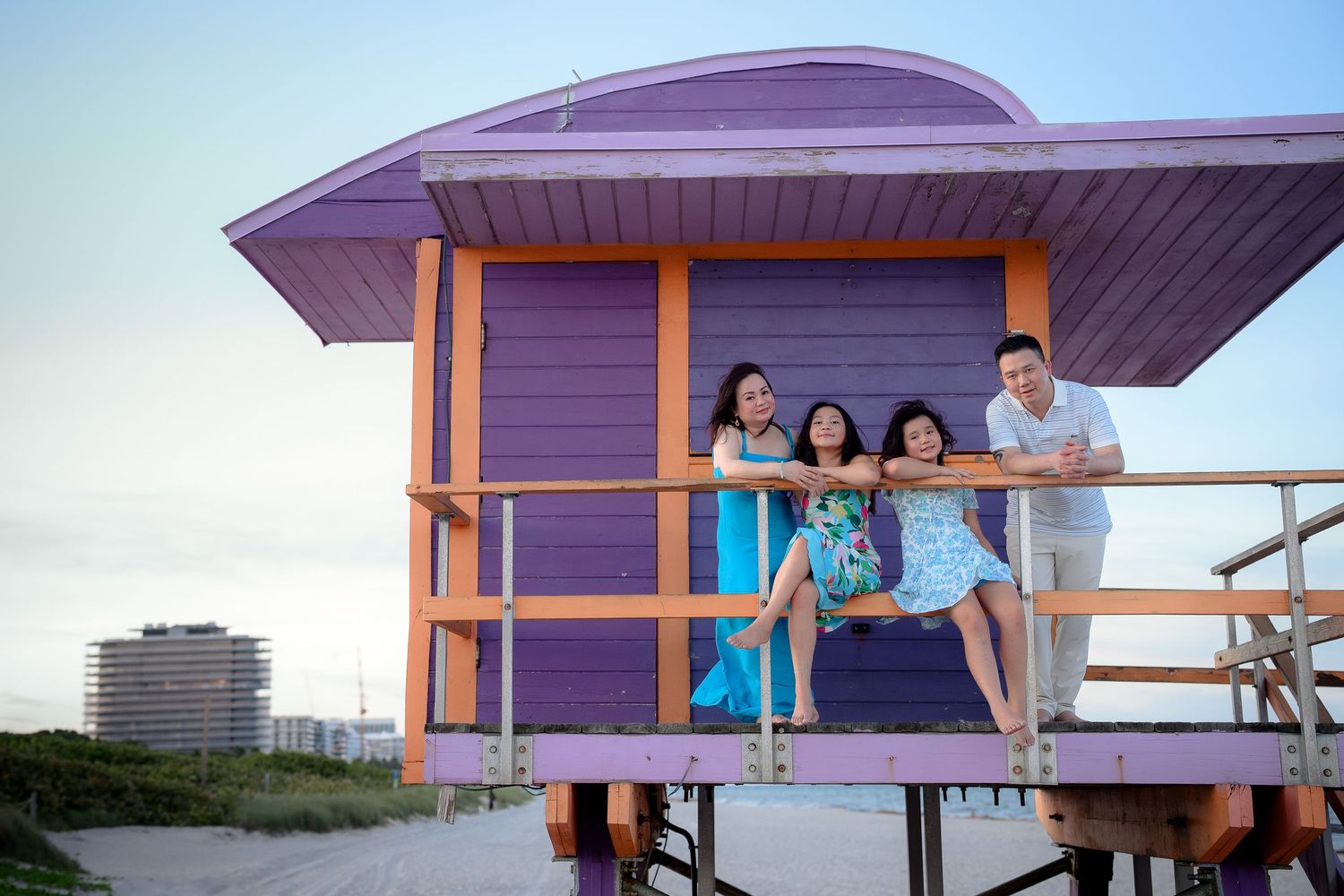 Family of four posing on a purple lifeguard stand on Miami Beach at sunset.