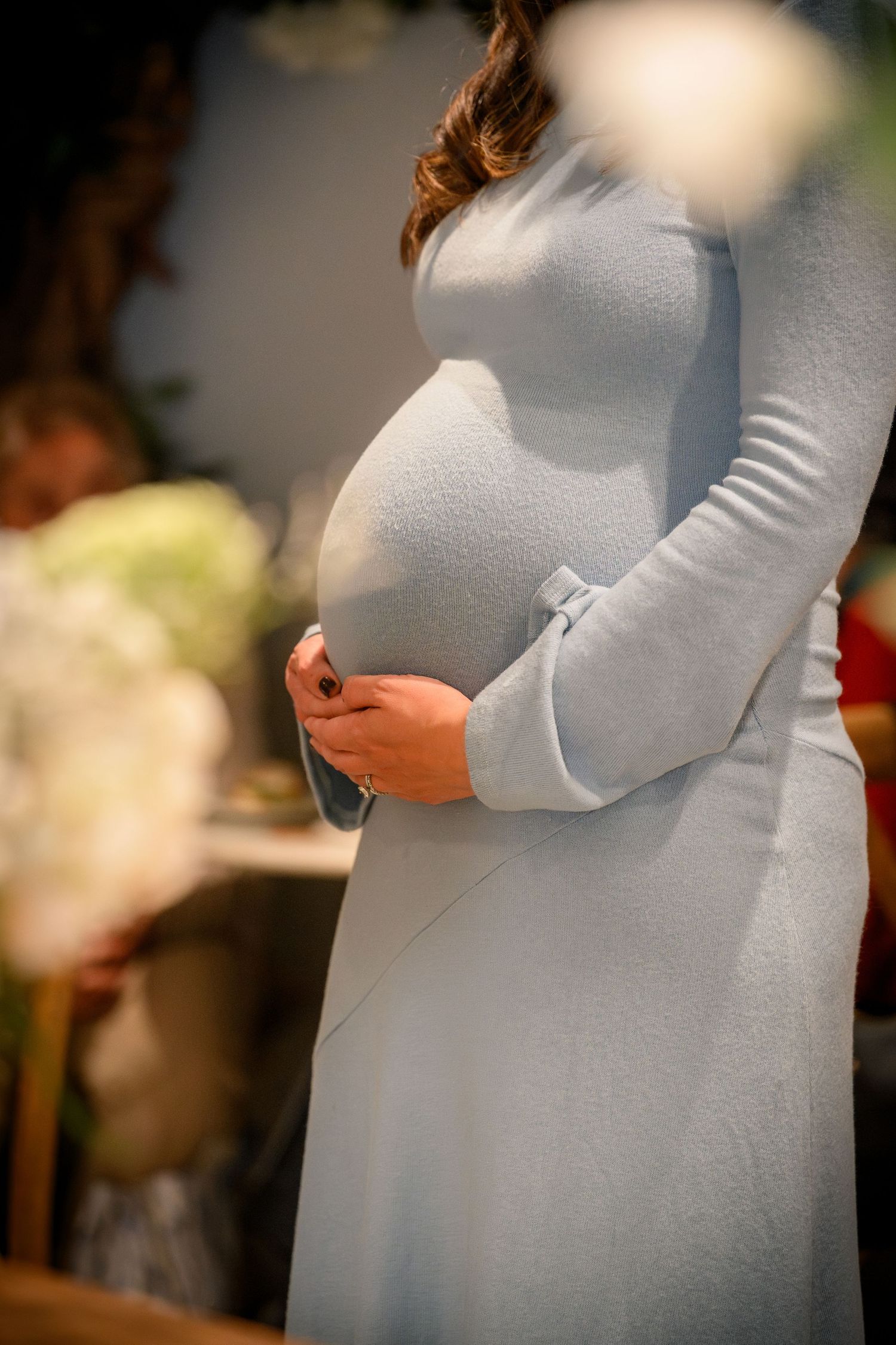 A series of close-up photos showing a pregnant belly in a light gray sweater from different angles.