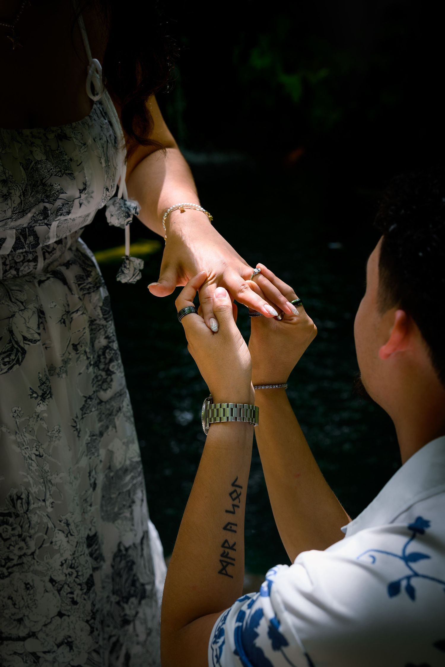 Person kneeling and holding hands with another during a romantic marriage proposal outdoors.