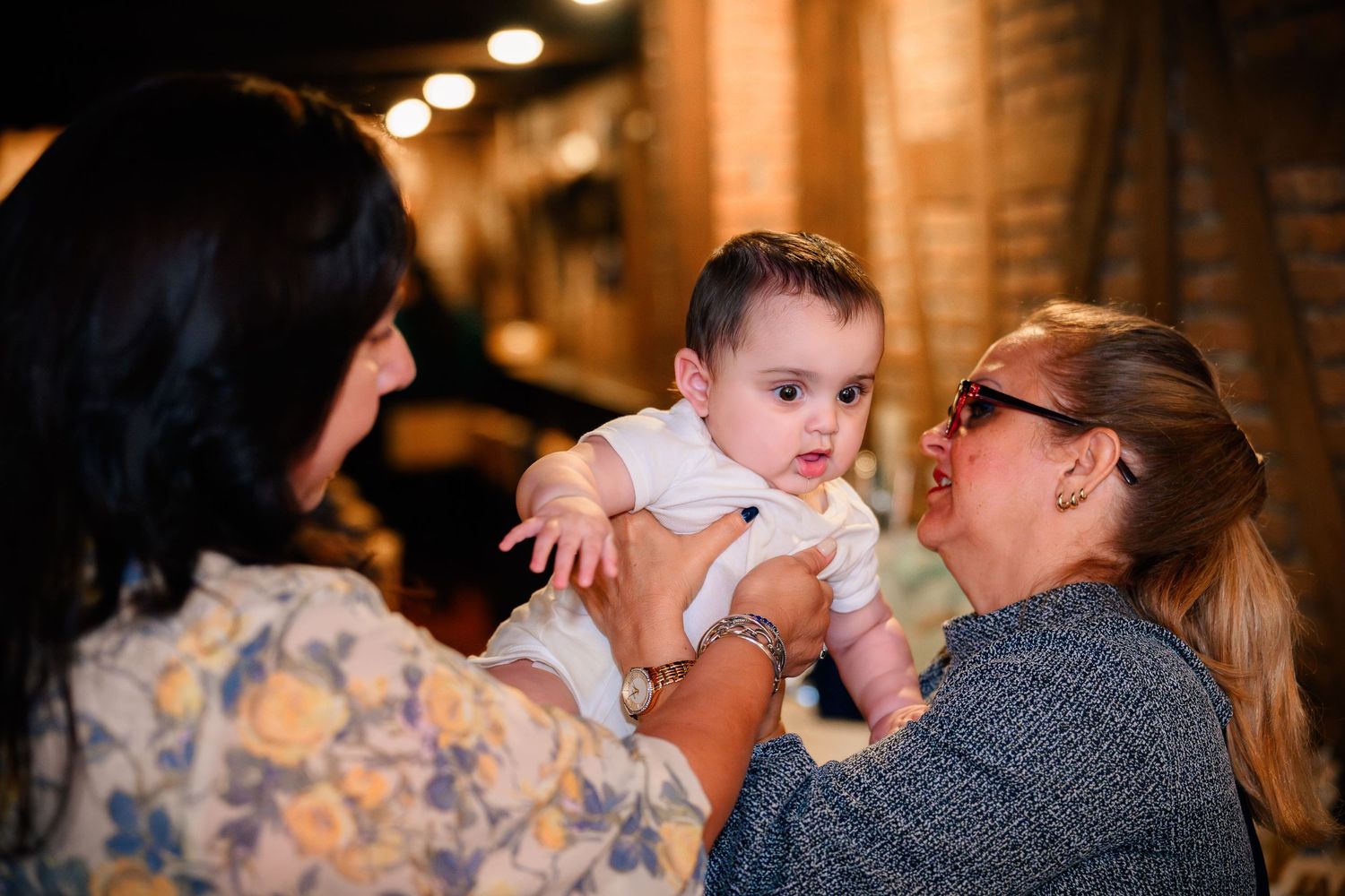 A tender moment captured during a wedding reception as guests dance in a warmly lit venue.