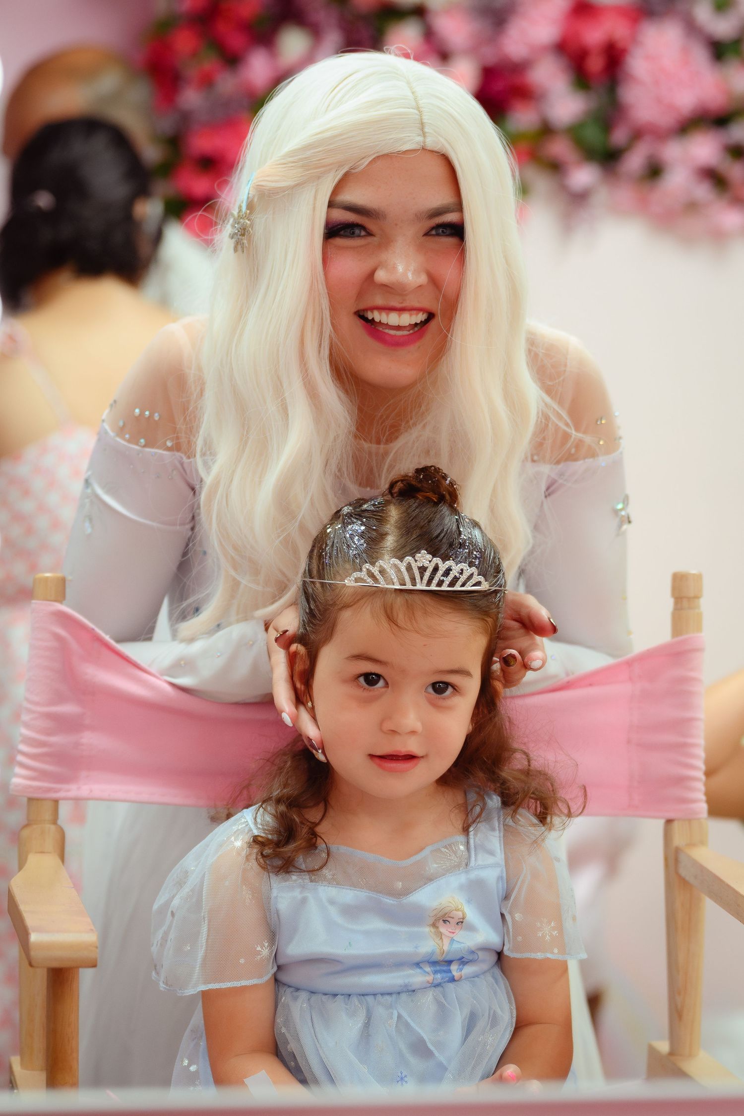 Woman in white Elsa costume posing with a young girl wearing a tiara at a princess-themed party.